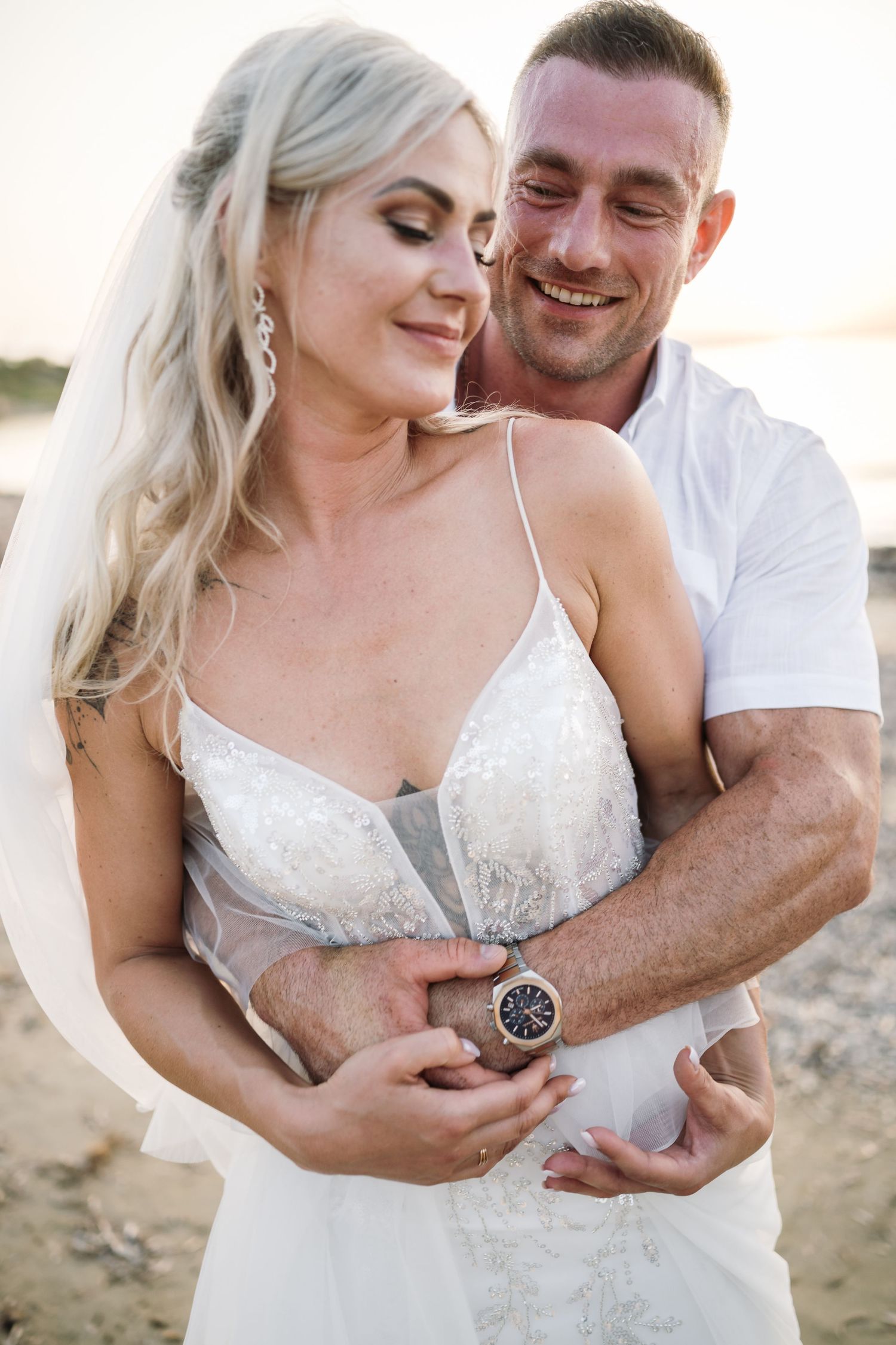 Intimate beach photoshoot featuring romantic embraces and tender moments at sunset.
