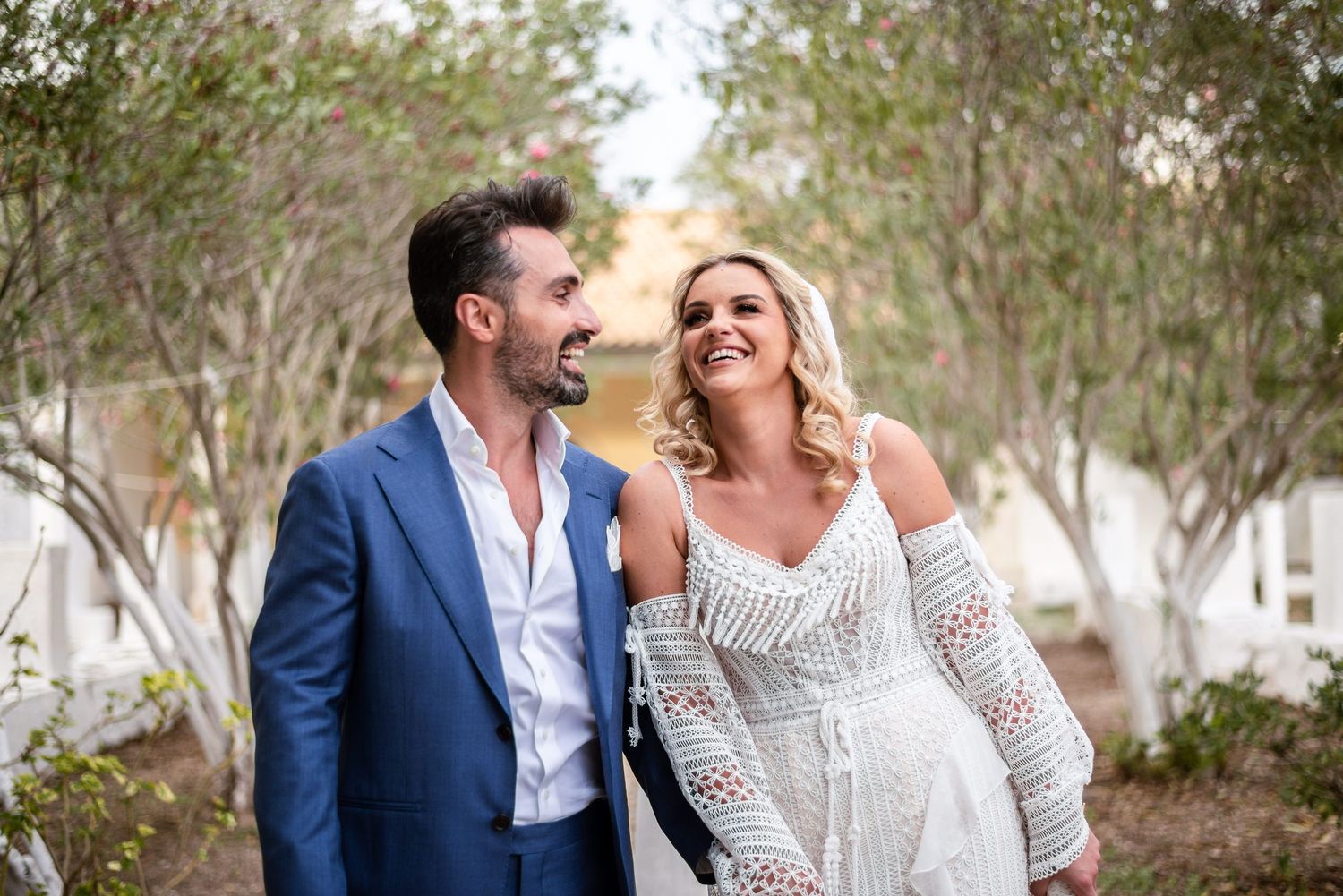 Romantic wedding couple walking together through a garden path.