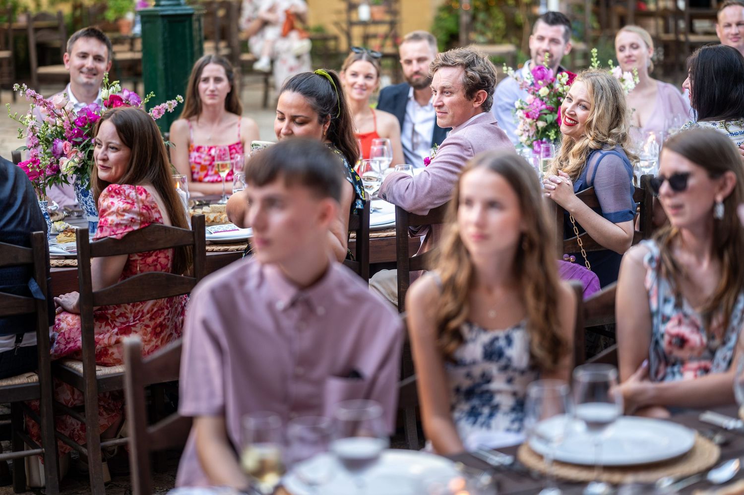 Guests seated at long tables during an outdoor summer wedding celebration.