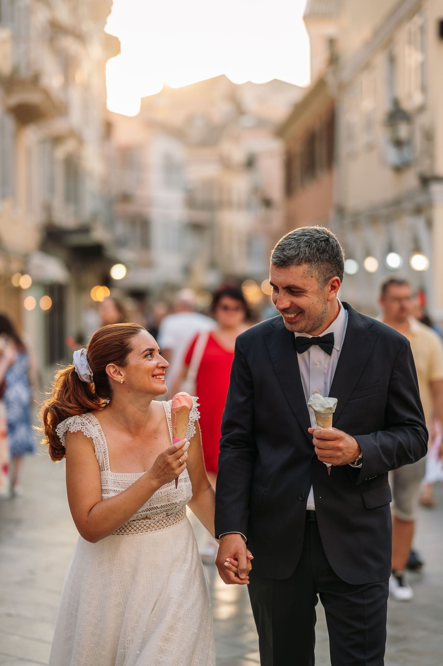 Couple enjoying gelato while walking through historic streets at dusk.