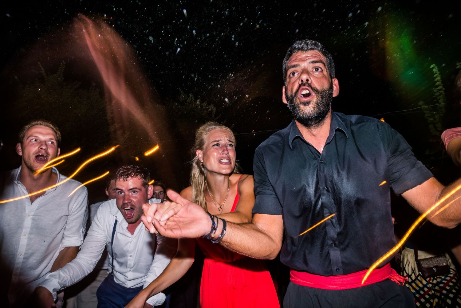 Energetic dance party at a nighttime wedding reception with guests celebrating.