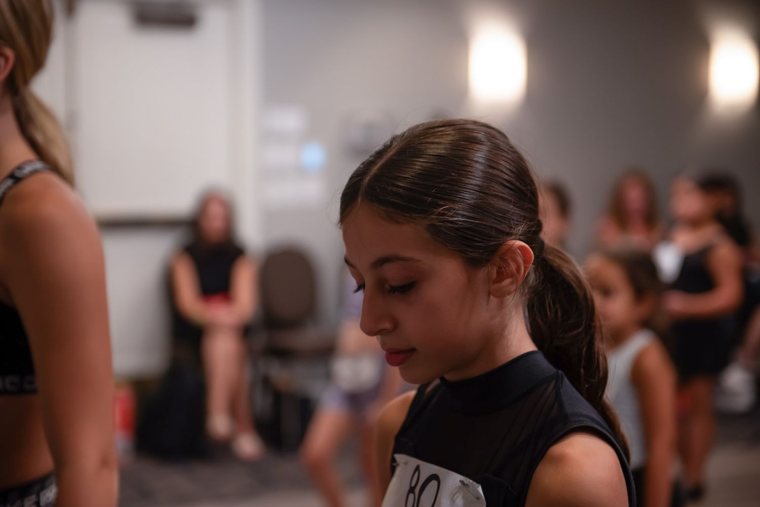 Young dancers in black leotards practicing ballet moves in a dance studio.
