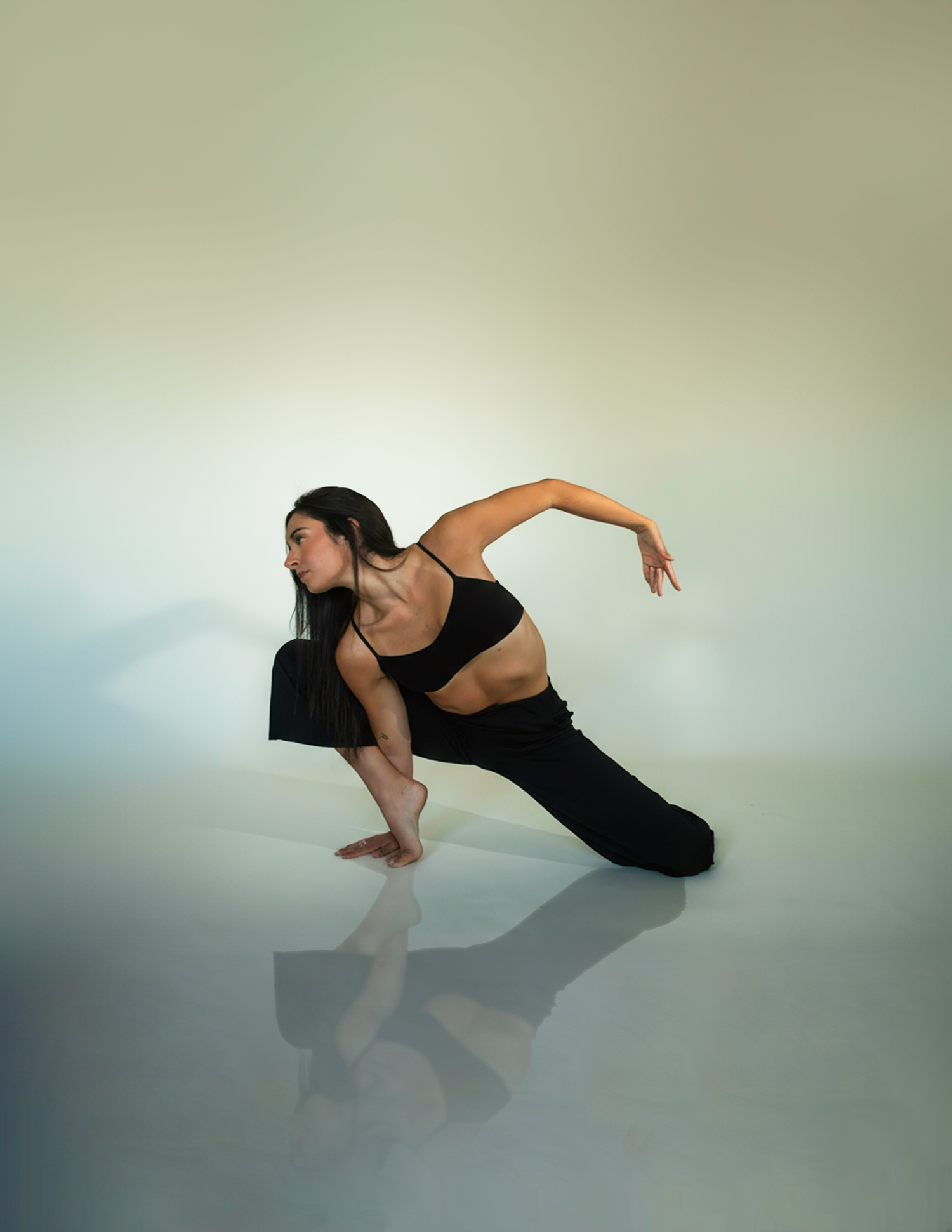 Contemporary dancer in black attire demonstrates graceful floor movement in studio setting.