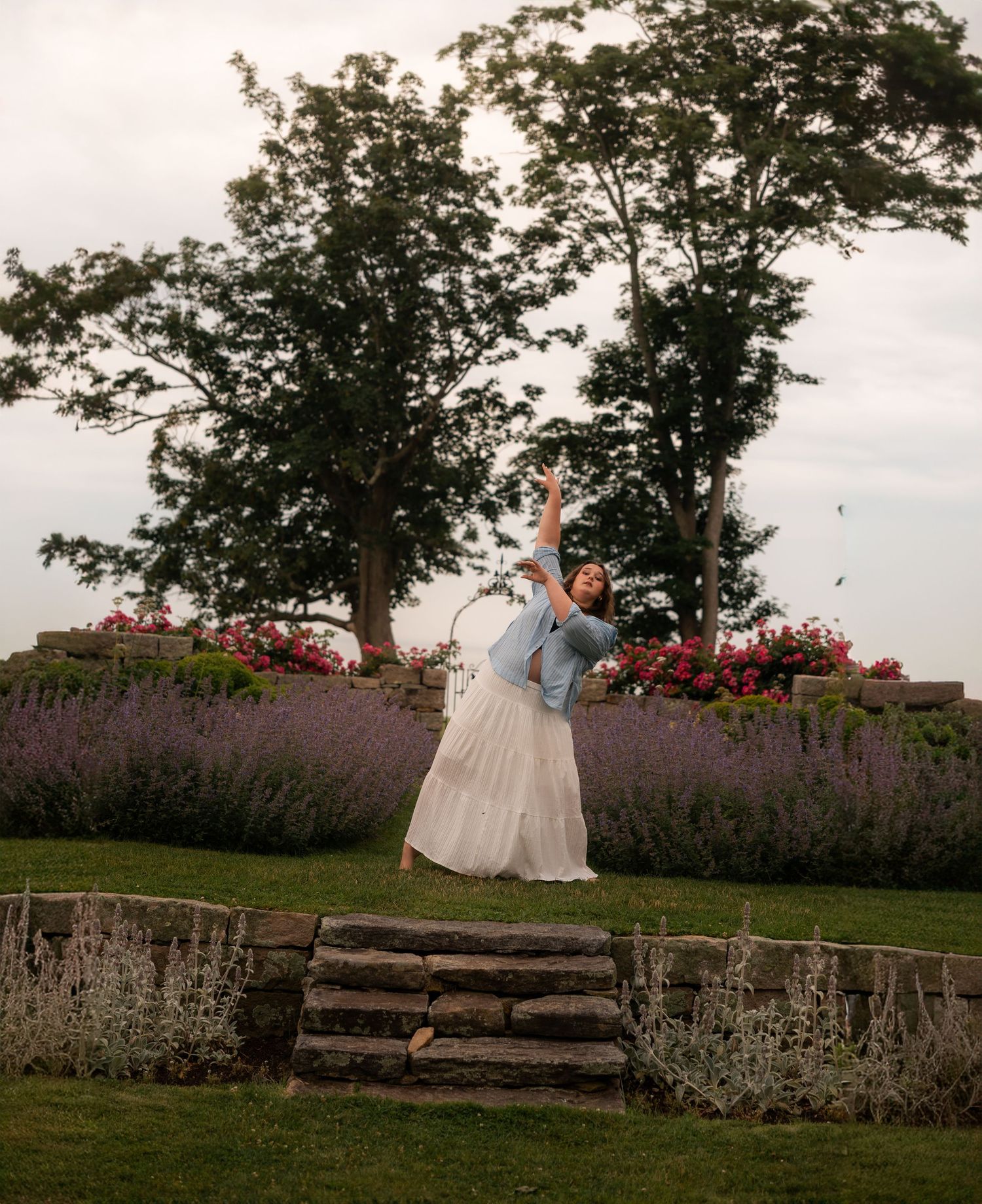 A couple dances joyfully in a lavender garden with colorful flowers and lush trees in the background.