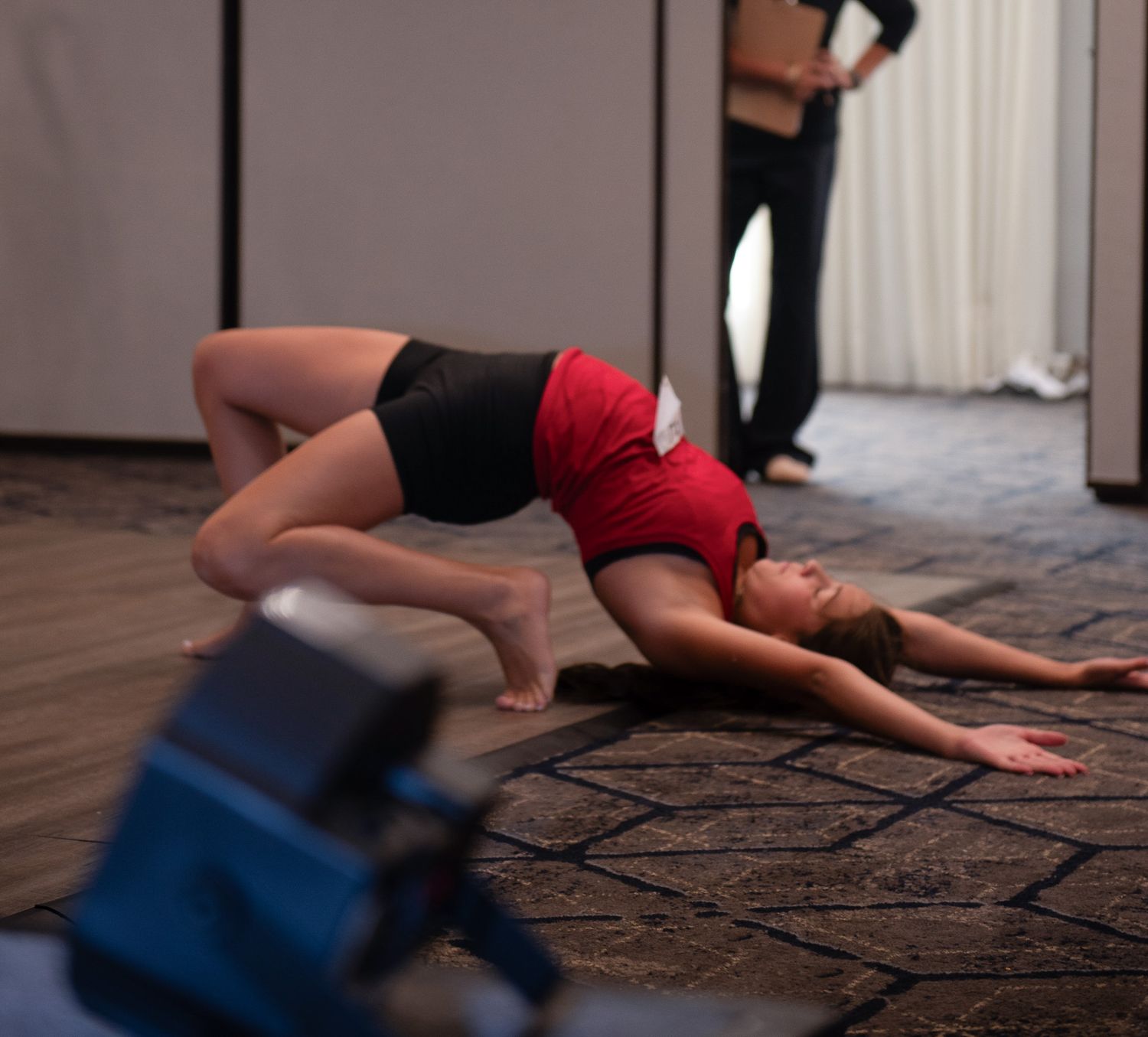 Dancer performs floor choreography sequence in red and black attire.