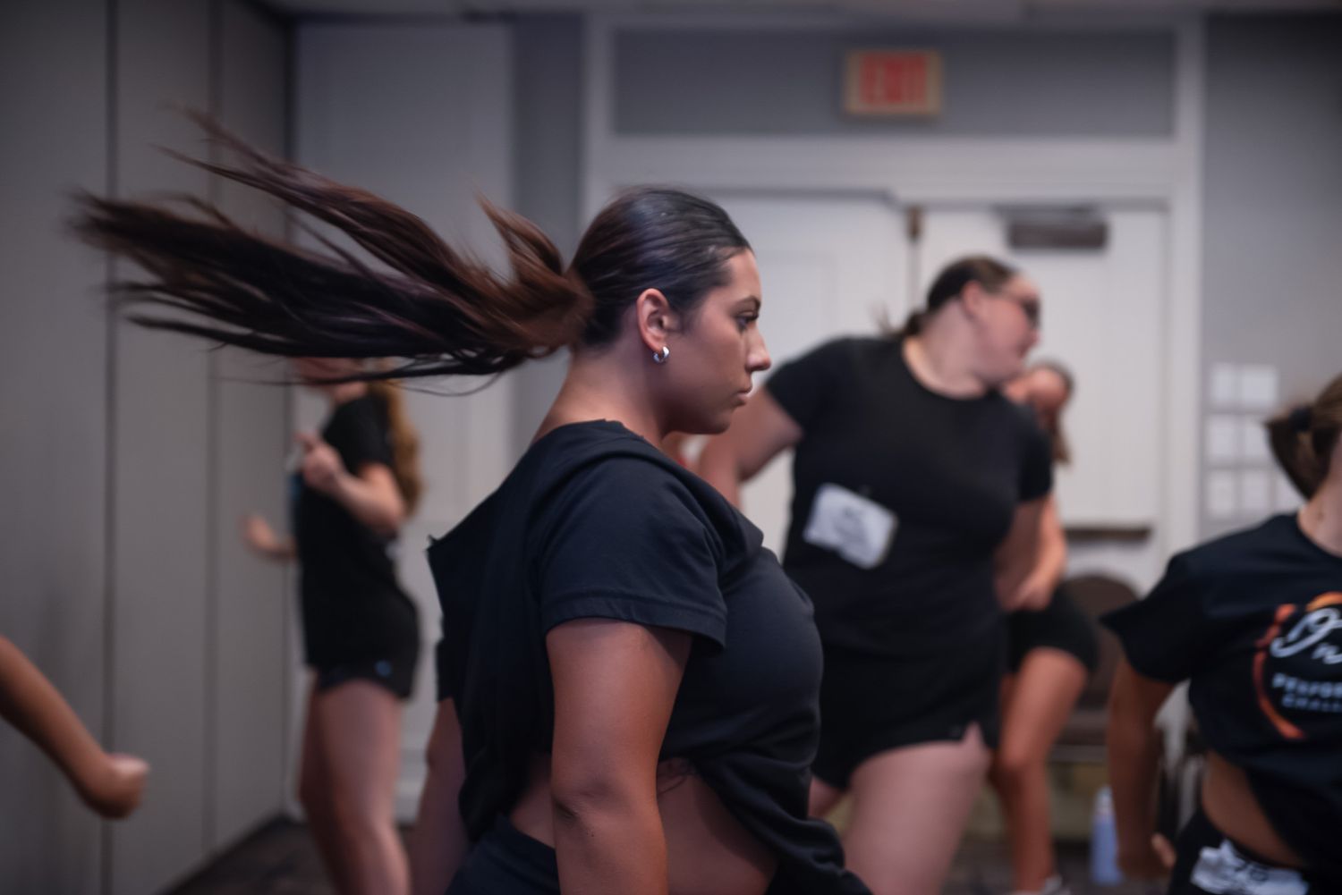 Dance class participants practicing choreography in studio with dramatic lighting.