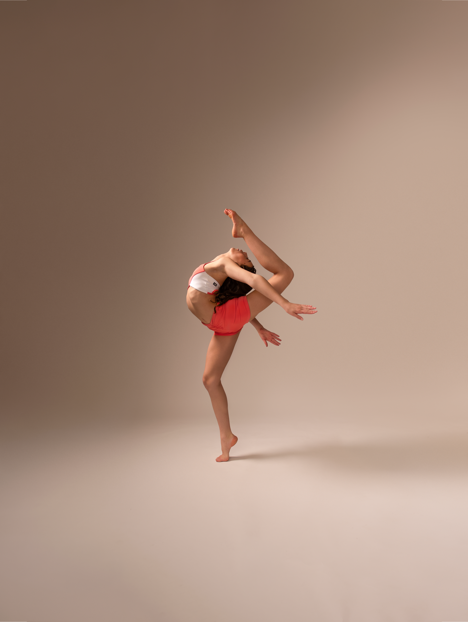 A dancer in a red outfit performs a graceful sequence of modern dance movements against a neutral studio backdrop.