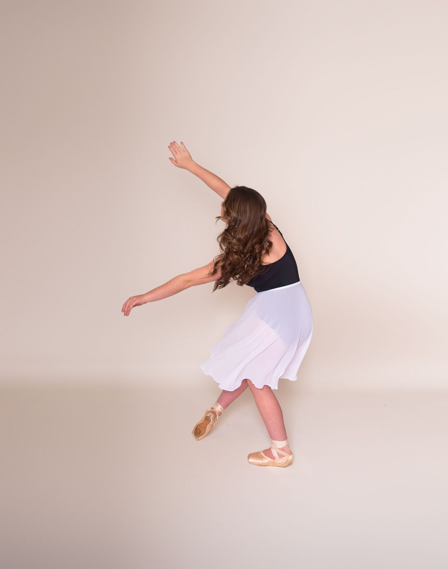 Dancer in white dress performing flowing movements in studio setting.