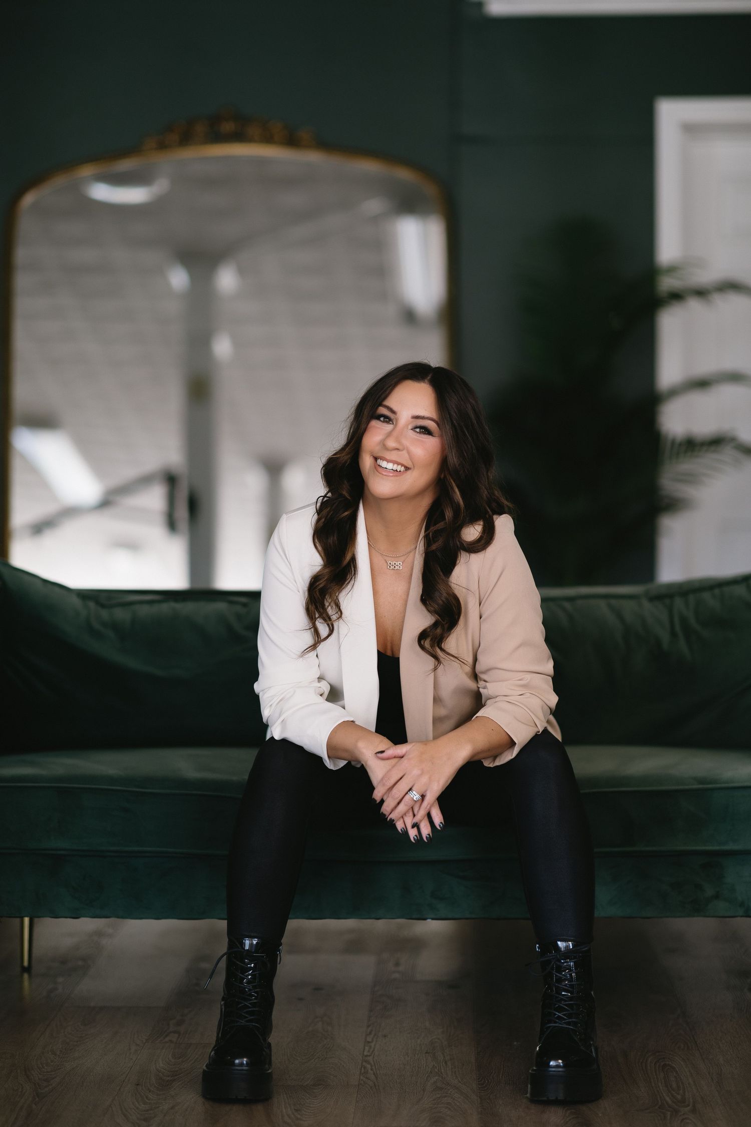 Casual lifestyle portrait of someone in business attire sitting on an emerald green couch.