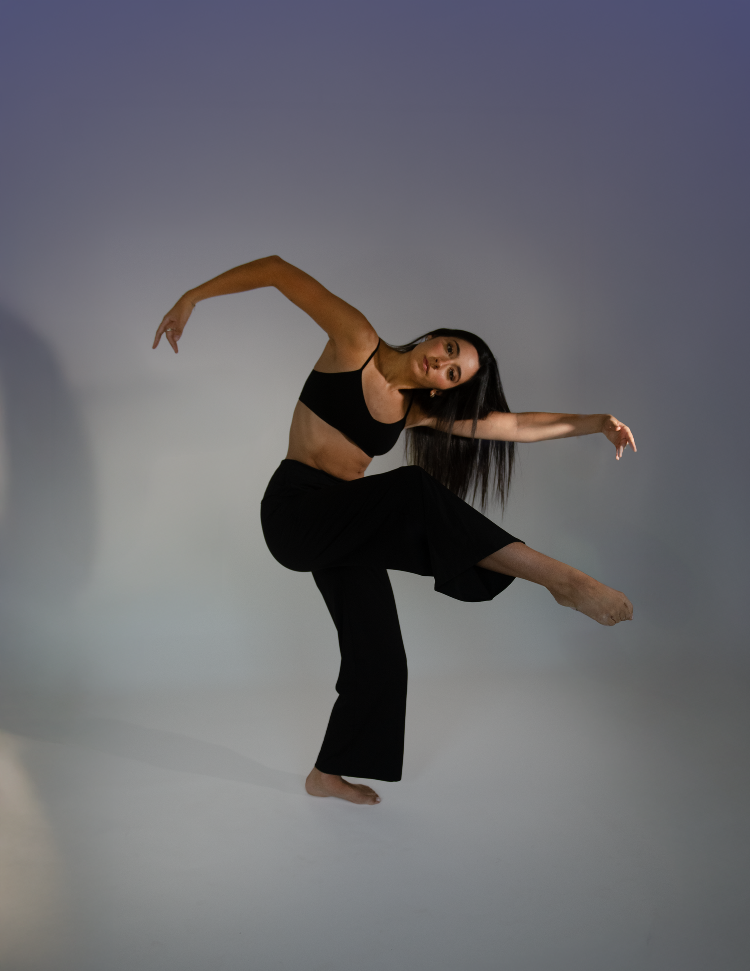 Modern dancer performs expressive movement in black outfit against gradient background.