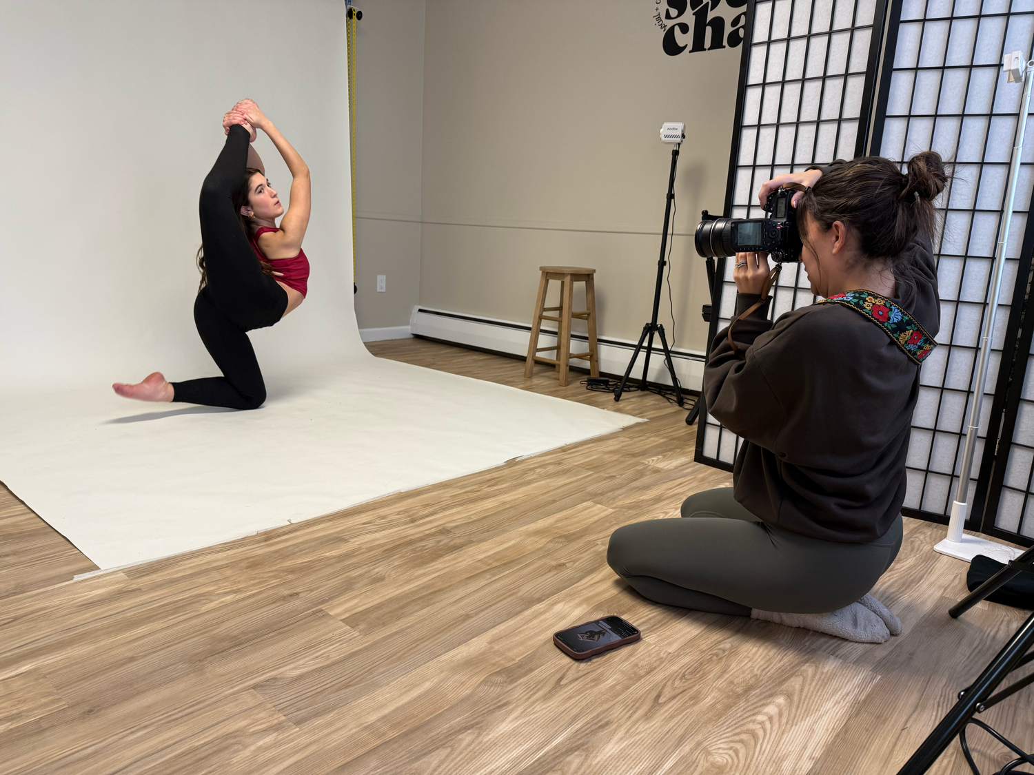 Photography session in progress showing studio setup with white backdrop and equipment.