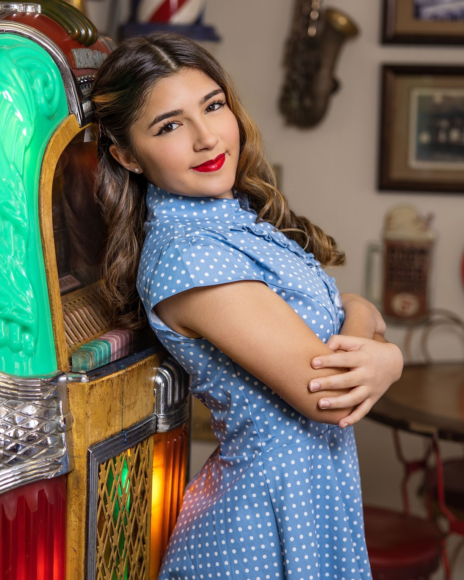 Vintage-inspired portrait in polka dot blue dress against retro jukebox.