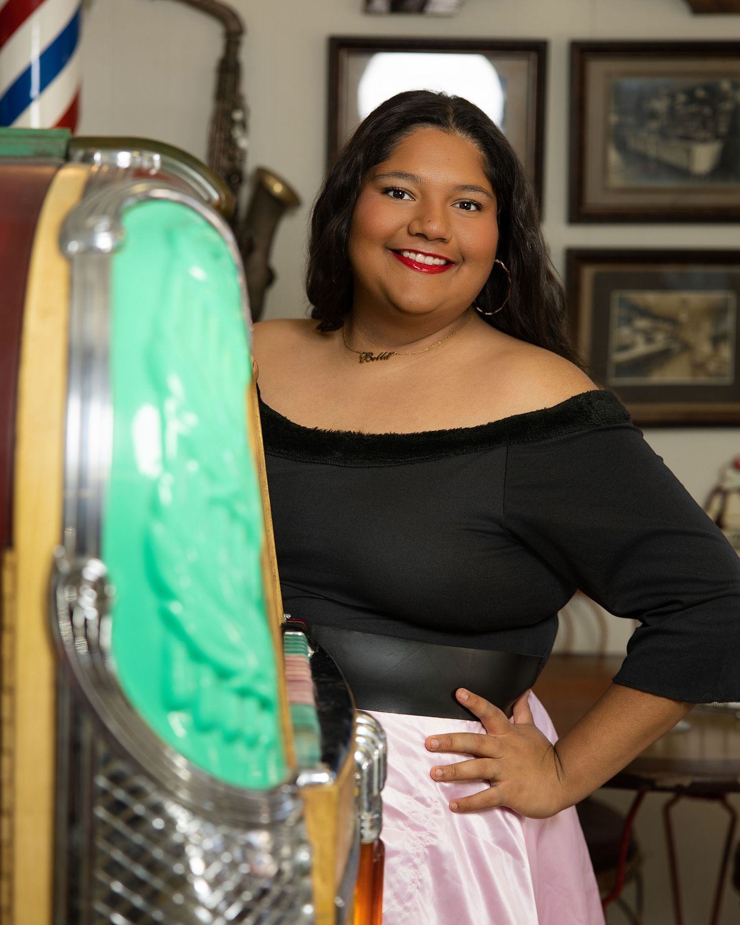 A person in a black off-shoulder top poses with a tall green lava lamp display in the background.