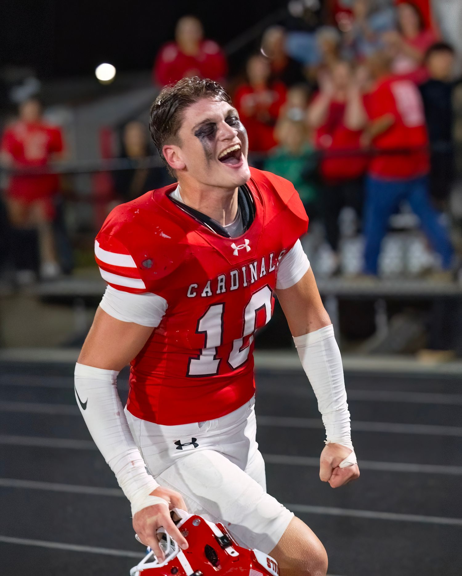 Football players in red Cardinals uniforms celebrate enthusiastically on the sidelines.
