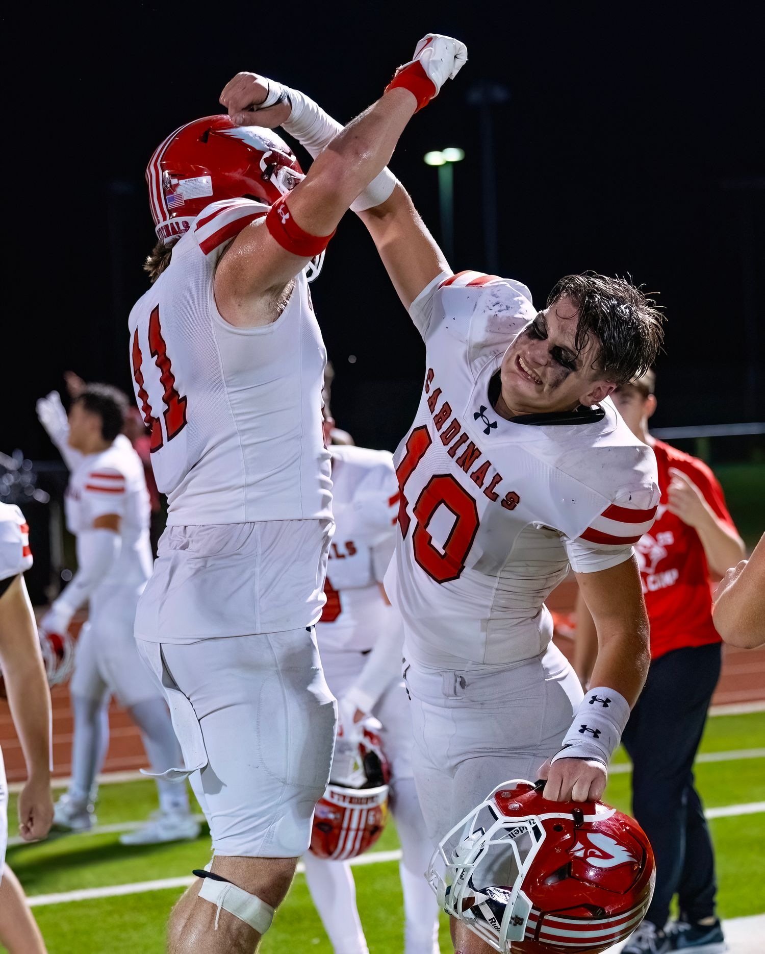 Football players in red and white uniforms stretch and warm up on the field during practice.