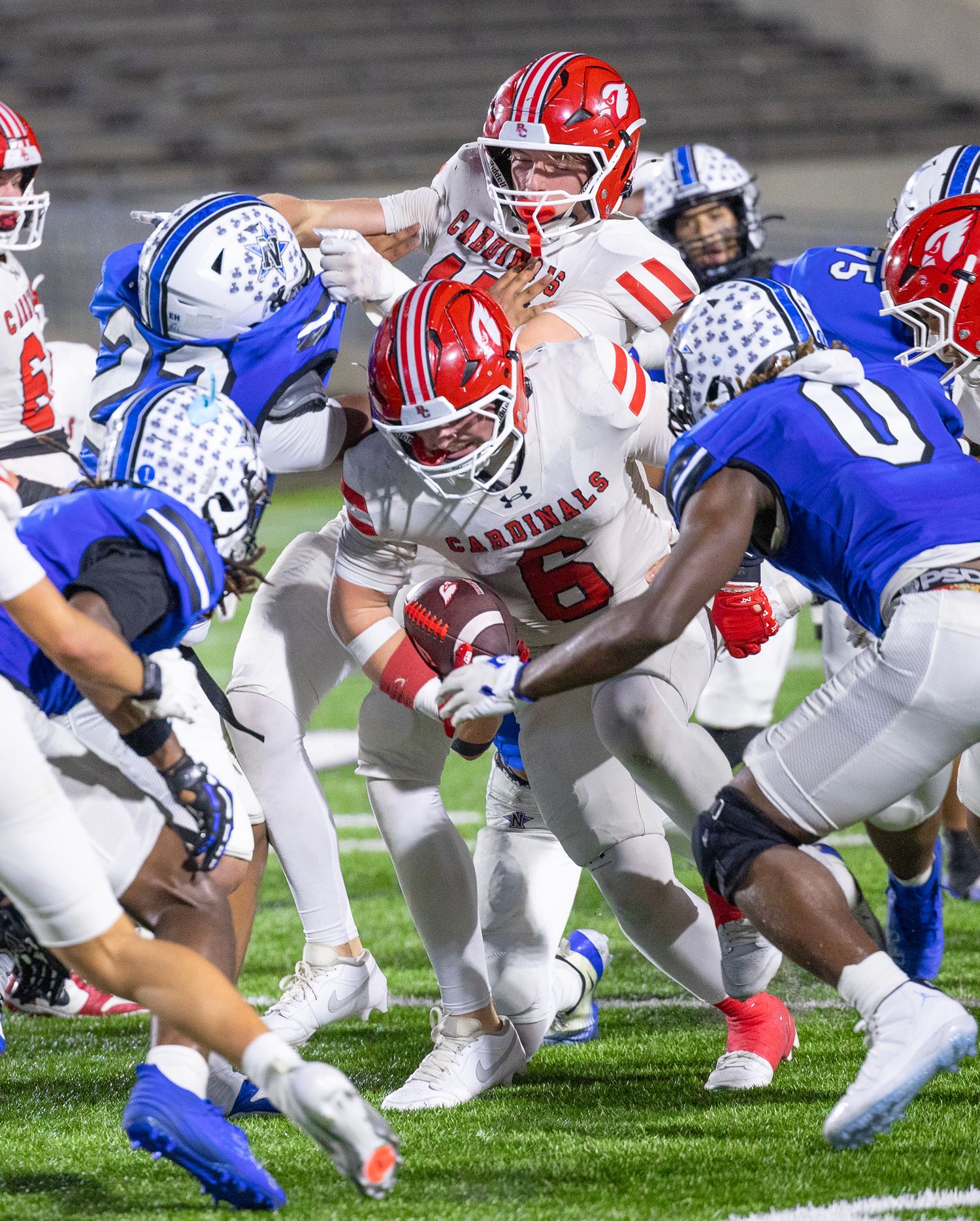 Football players from opposing teams in red and blue uniforms line up at the line of scrimmage during a game.
