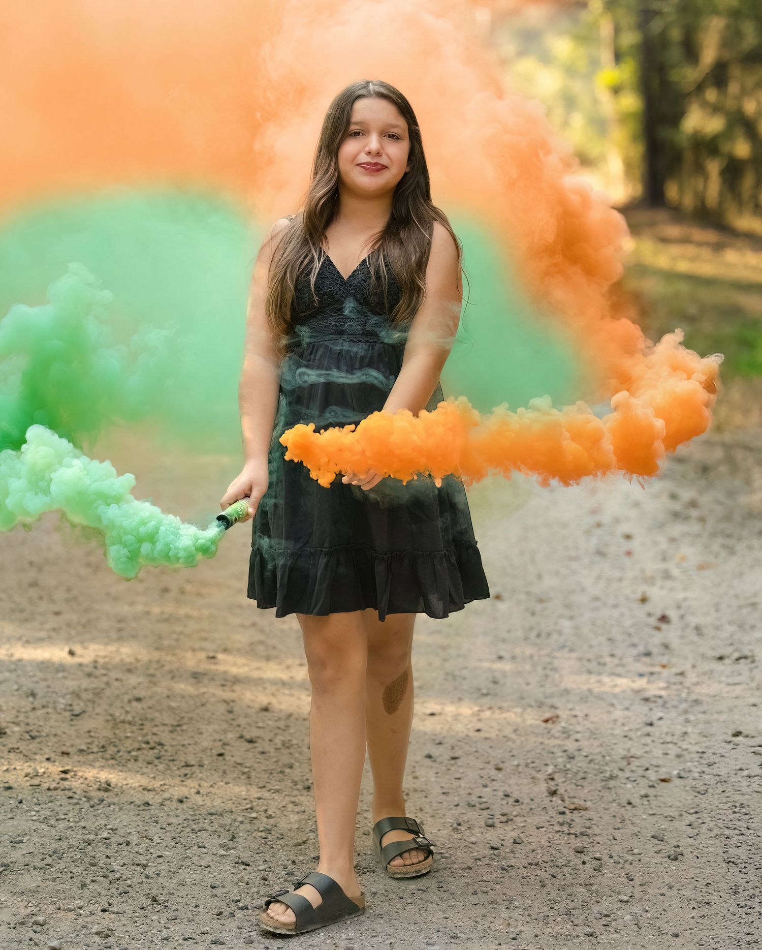 Portrait with orange and green smoke effects on dirt path.