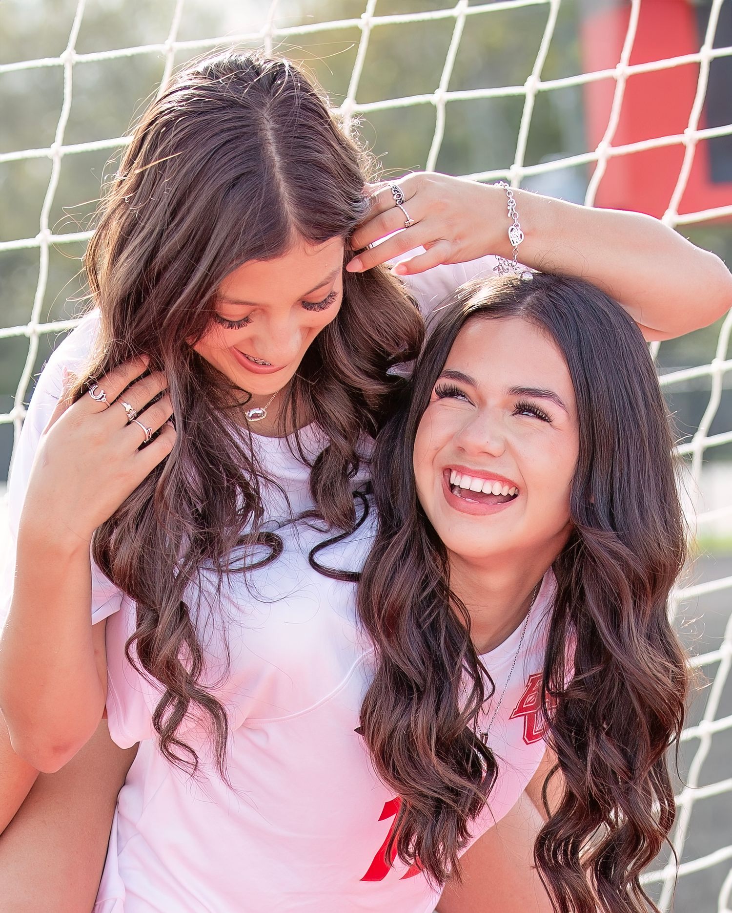 A group of women with long dark hair laugh and smile together in a candid outdoor photo series.