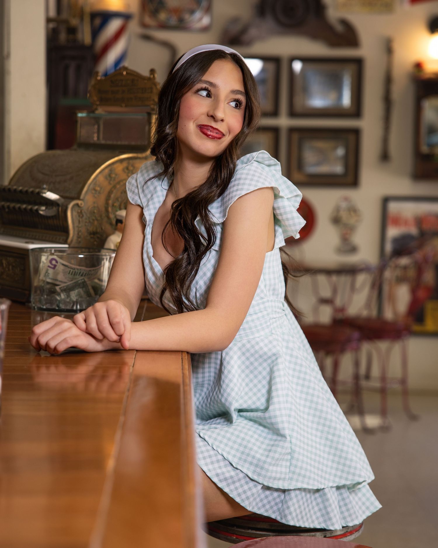A vintage-inspired photo shoot in a diner setting showcases a light blue checkered dress.