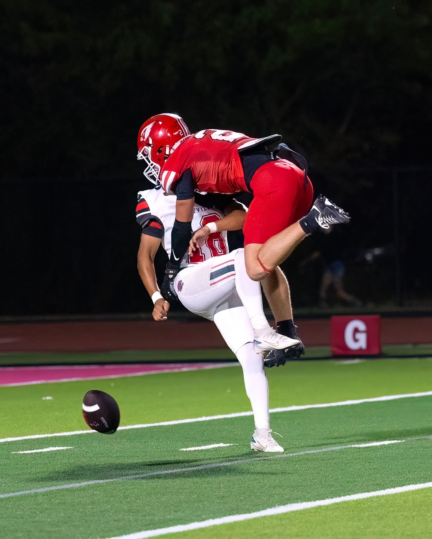 A sequence of action shots shows a football player performing a forward somersault flip on a sports field at night.