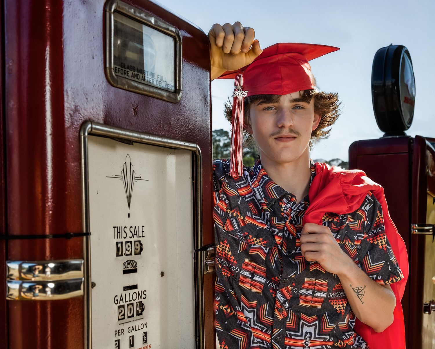 Person in red baseball cap and patterned shirt poses against dark red wall in vintage train car interior.