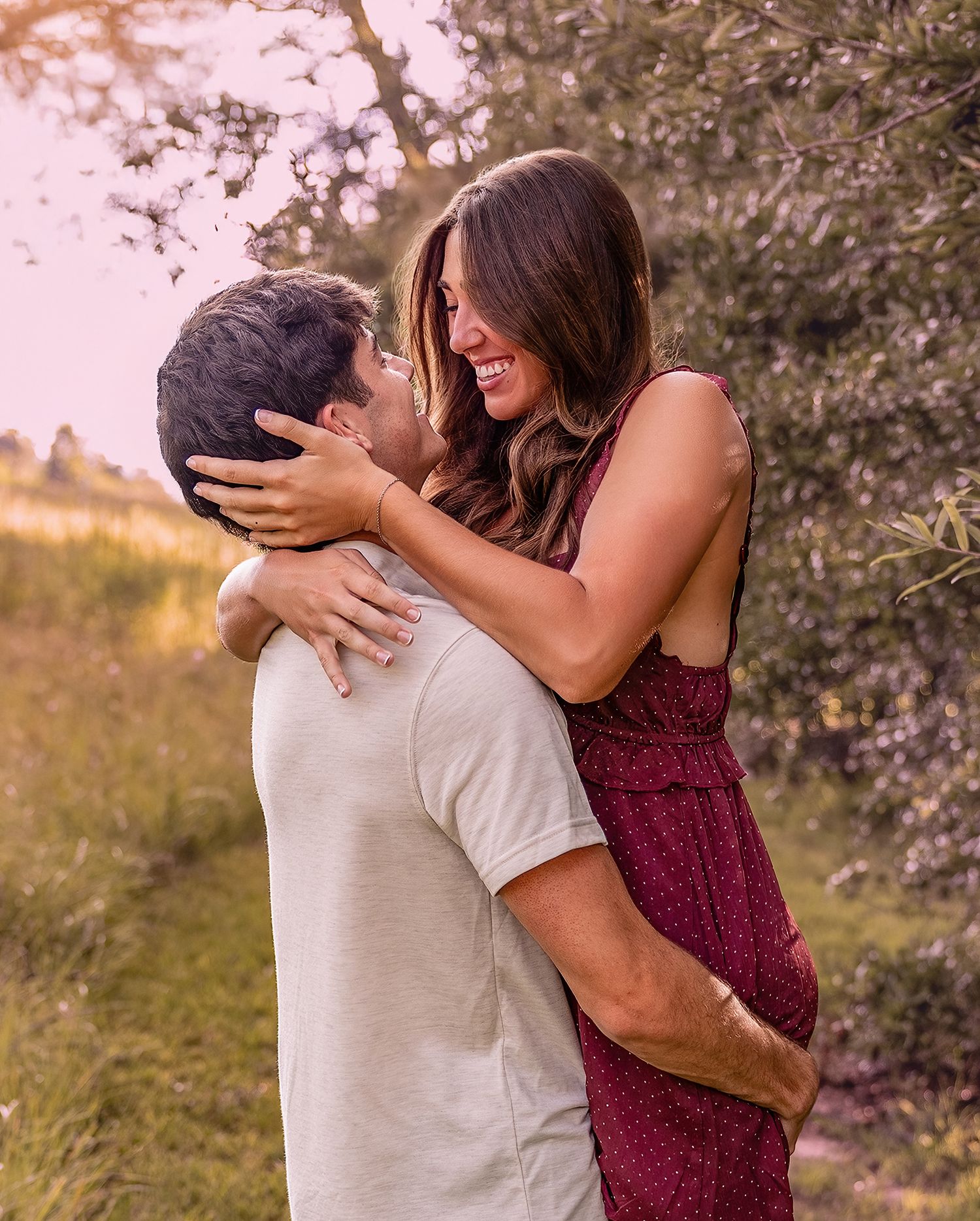 A couple embraces tenderly during a romantic sunset photoshoot in a natural outdoor setting.