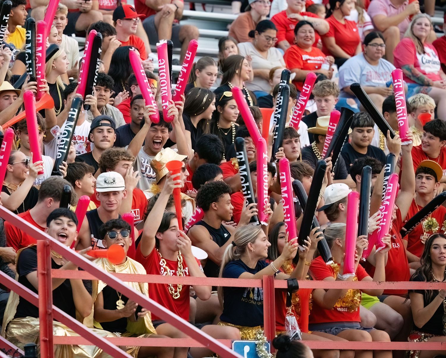 Sports fans wave pink thunder sticks in a packed stadium crowd during an exciting game.