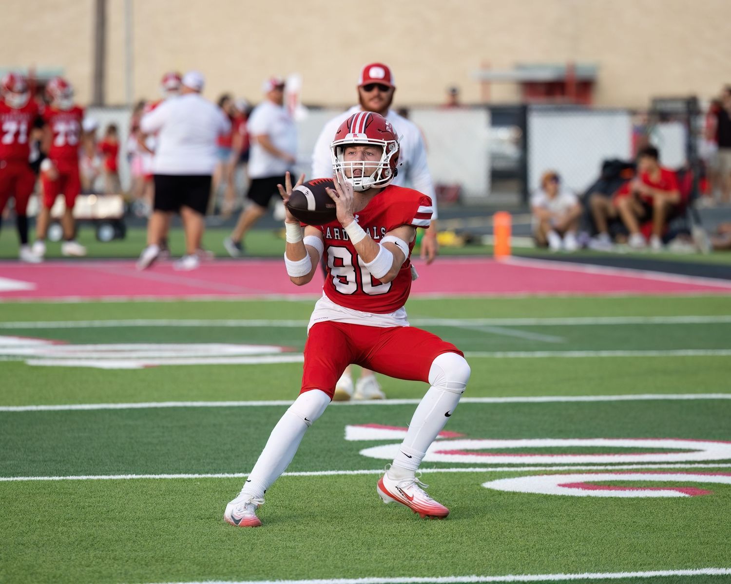 Football player in red uniform catches the football.