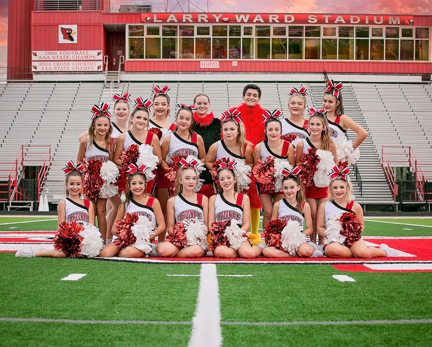 Group of cheerleaders pose together on football field at Larry Ward Stadium during team photo session.