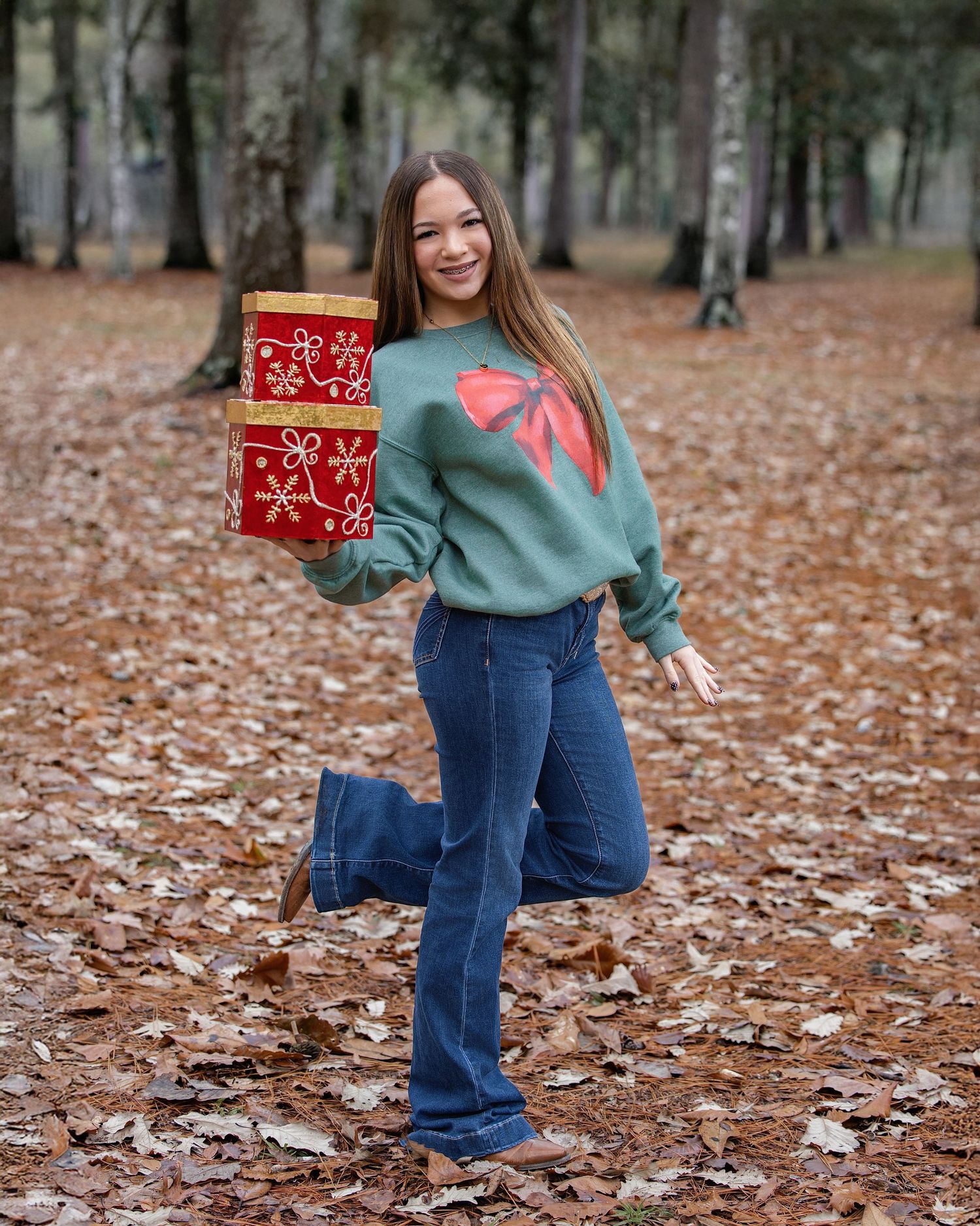 Fall fashion photoshoot featuring a teal sweater and jeans among autumn leaves.