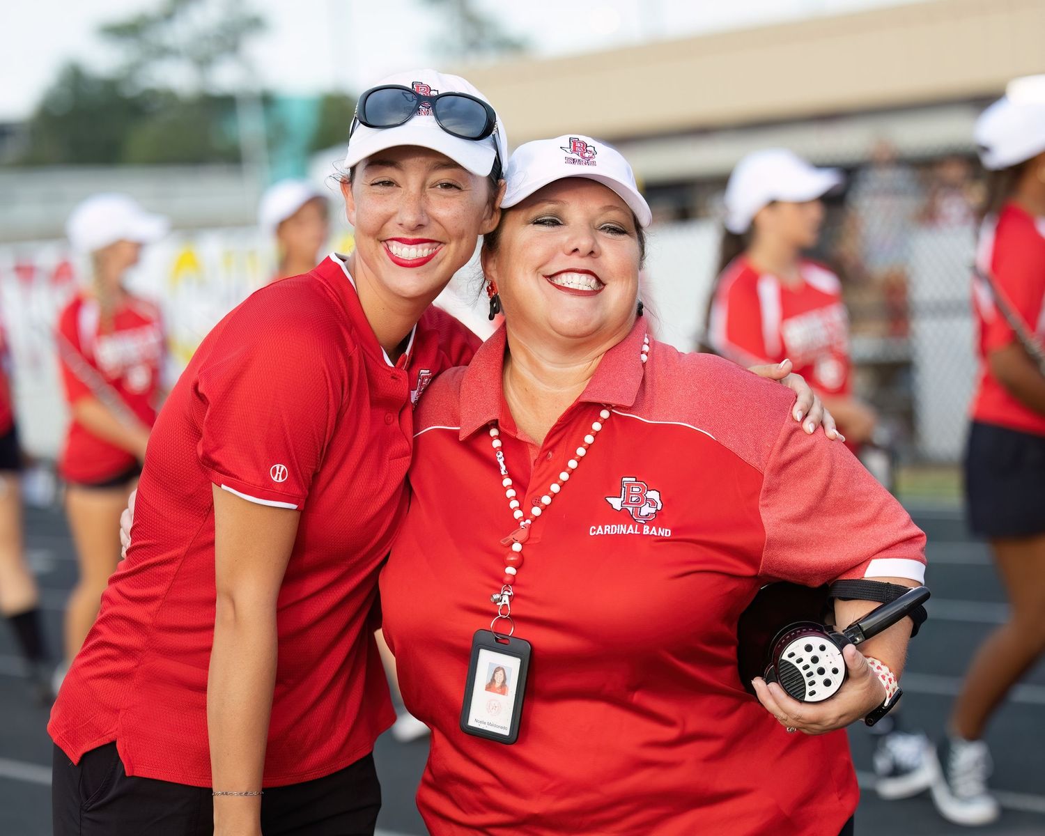 Group wearing matching red polo shirts pose together at a sports event.