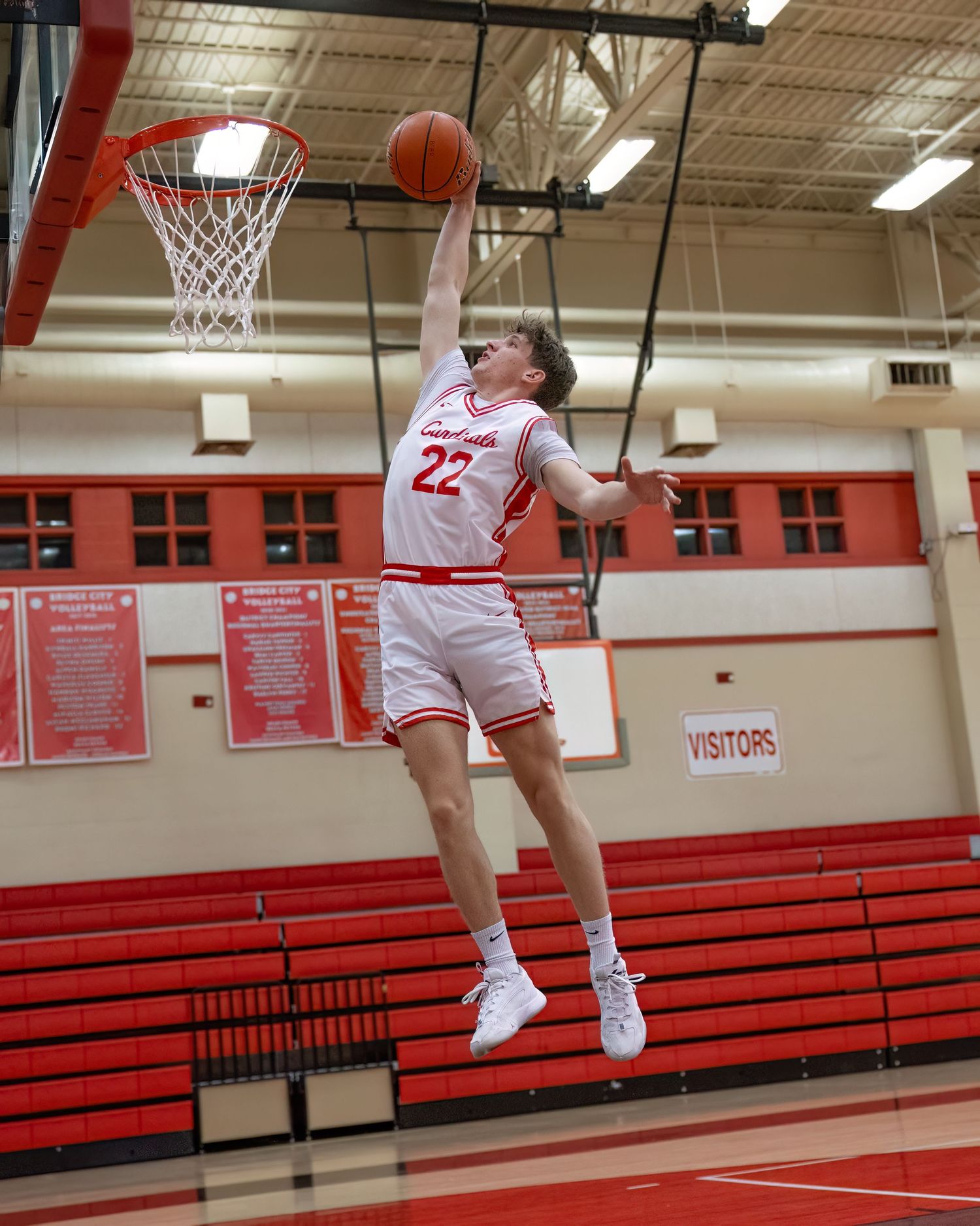 A basketball player in white uniform performs a slam dunk sequence across multiple action shots in a red gymnasium.
