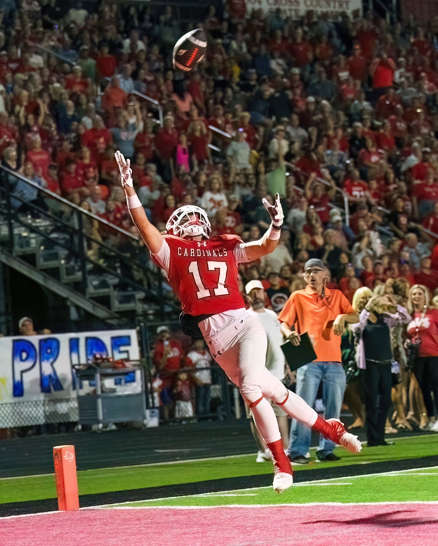 Action Photography captures Football player in red jersey diving dramatically into the end zone during an exciting touchdown celebration.