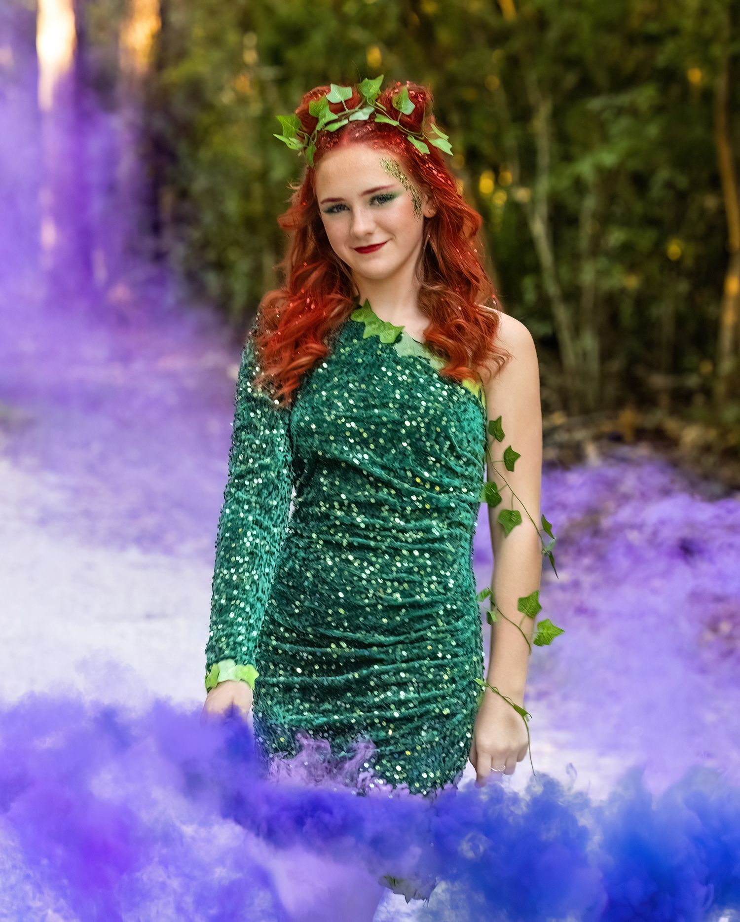 A sparkling emerald green dress creates drama with purple smoke effects in a forest setting.