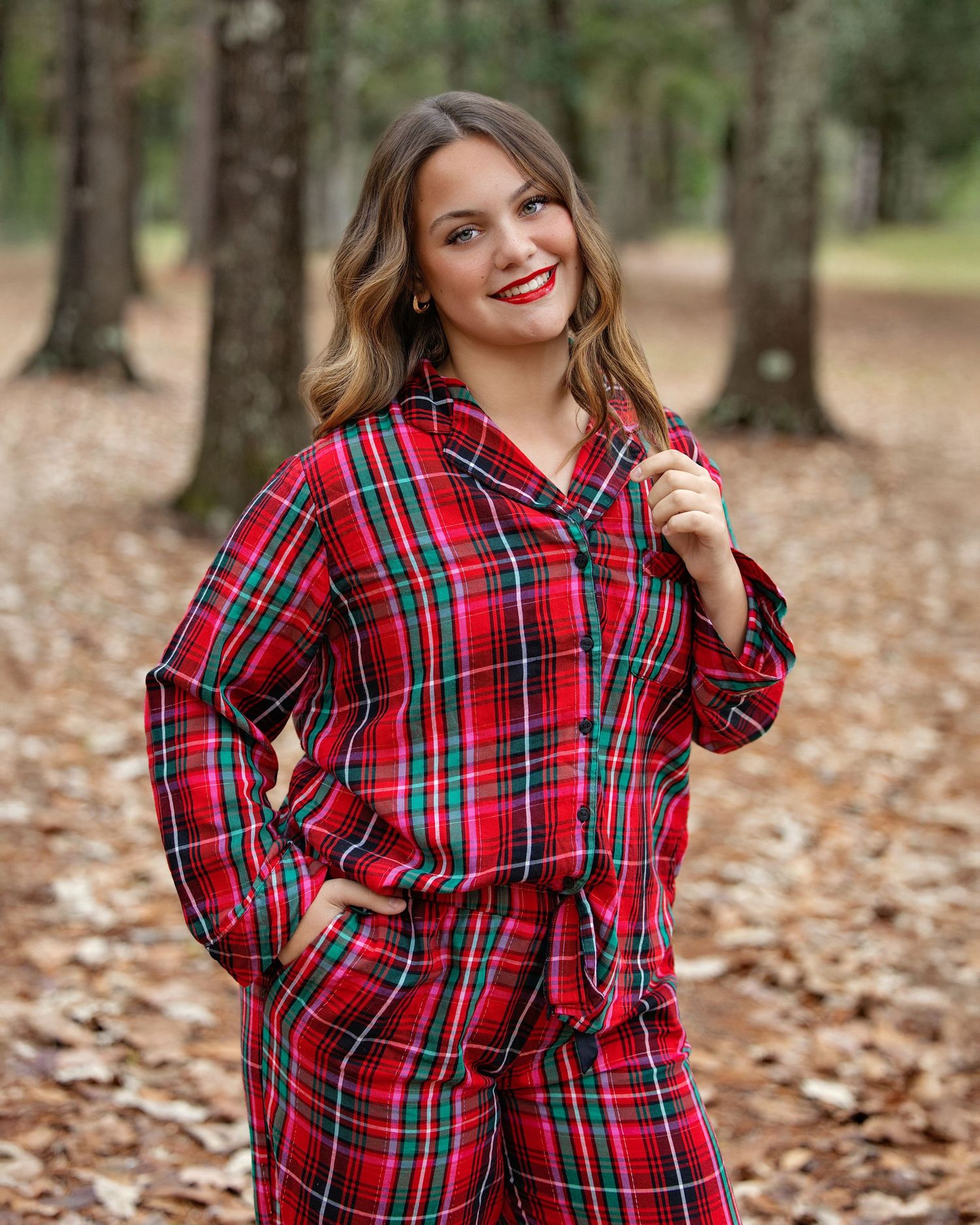 Holiday portrait session with red plaid flannel shirt against a backdrop of fallen leaves.