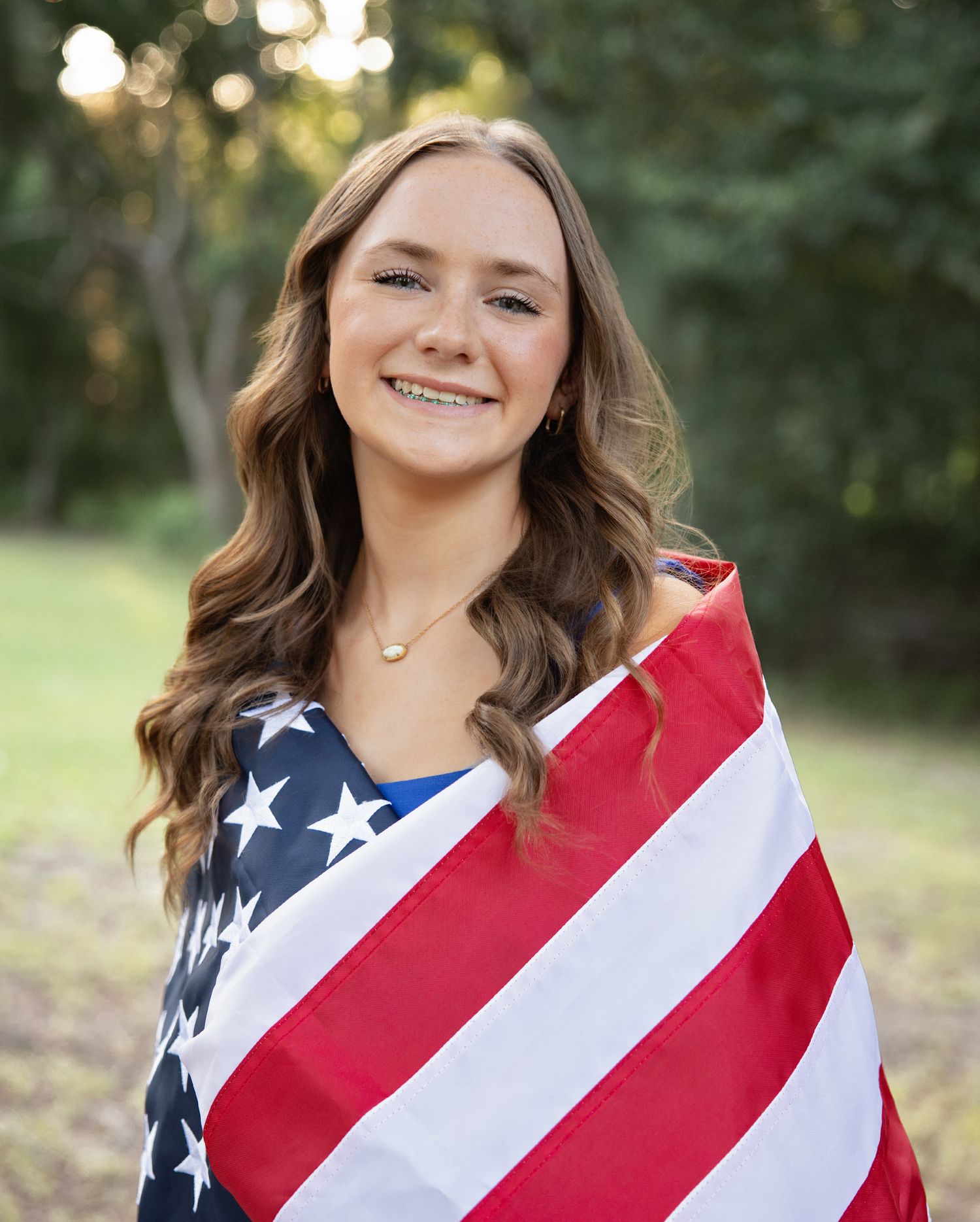 Outdoor portrait with American flag wrap and casual patriotic styling in natural setting.