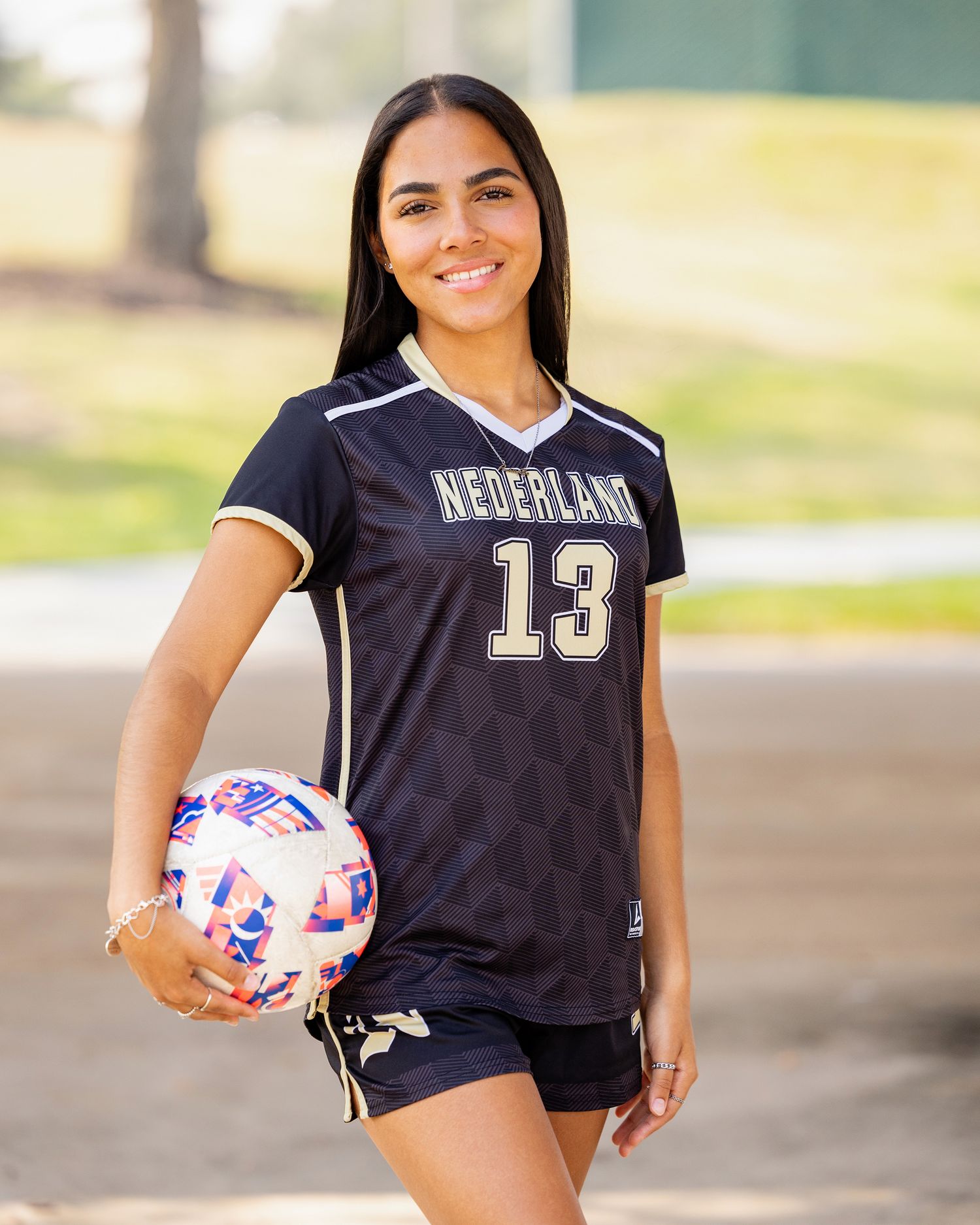Soccer players in Nederland jerseys pose with colorful soccer balls during team photo session.