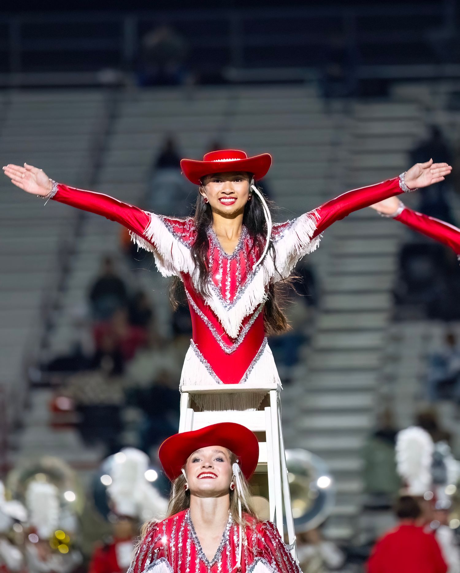 Performers in red and white western outfits dance with arms raised during a halftime show.