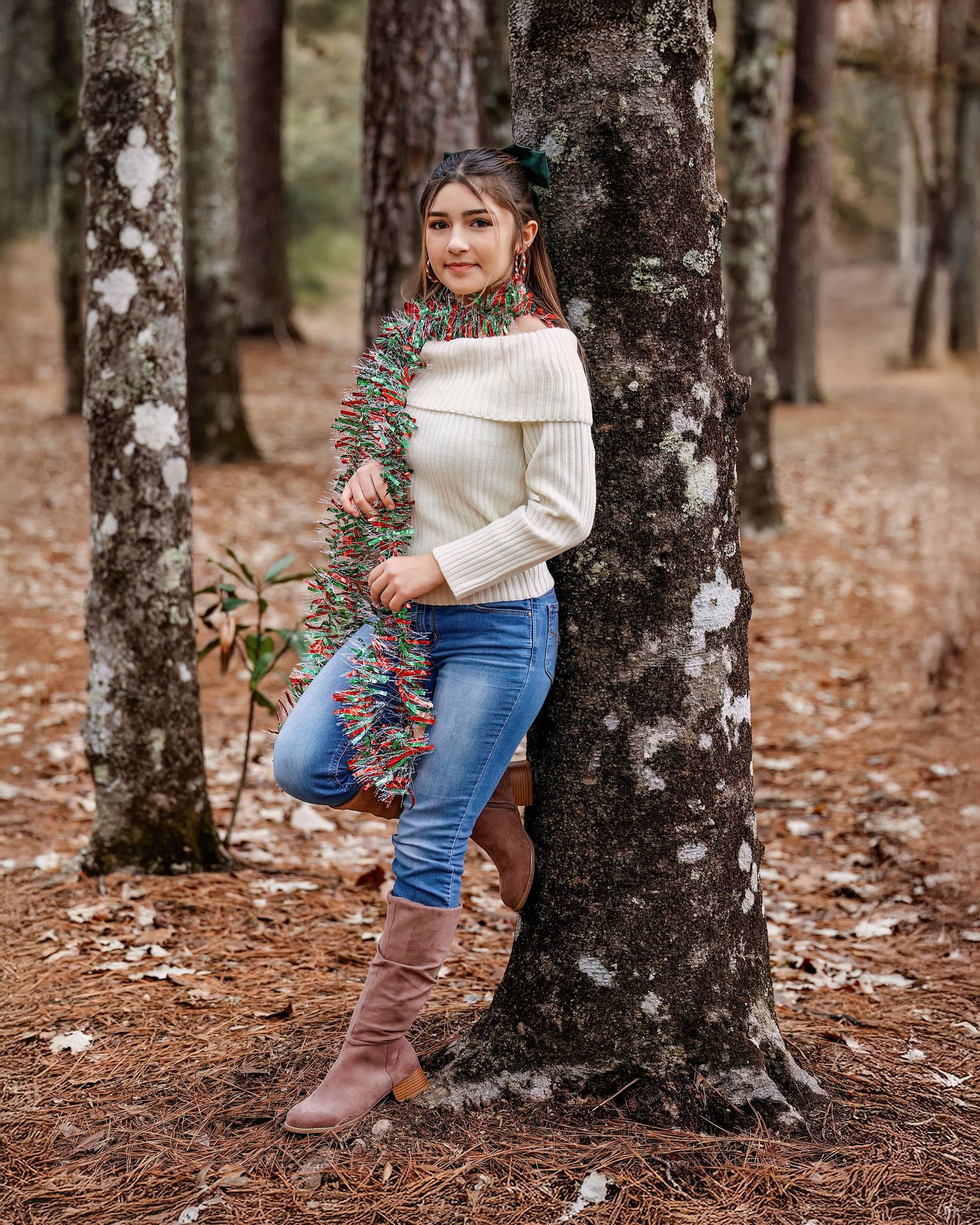 Person in white sweater and jeans poses against autumn trees in a woodland setting.