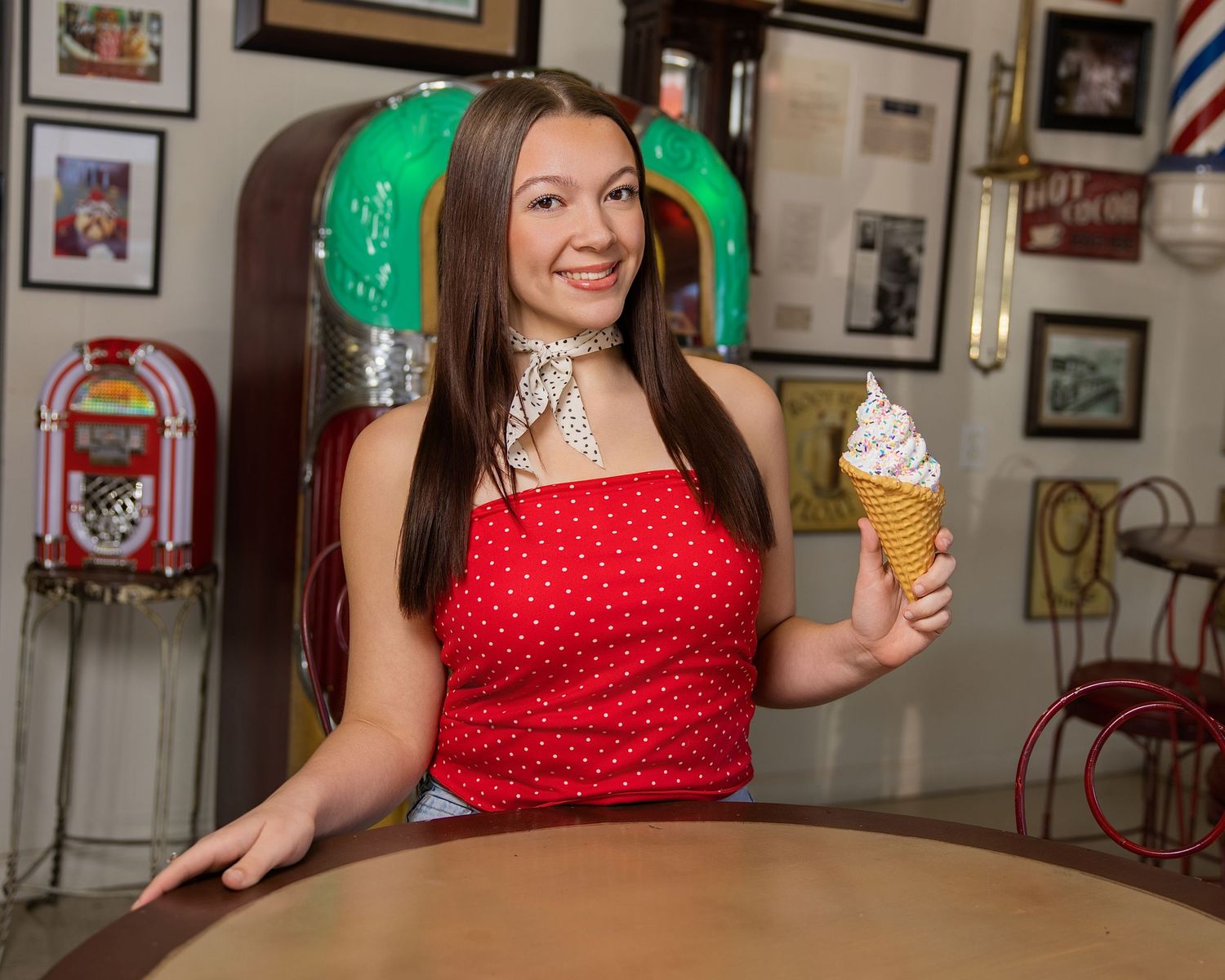 Person in red polka dot dress sits at bar counter with beer glass and green neon lighting in background.