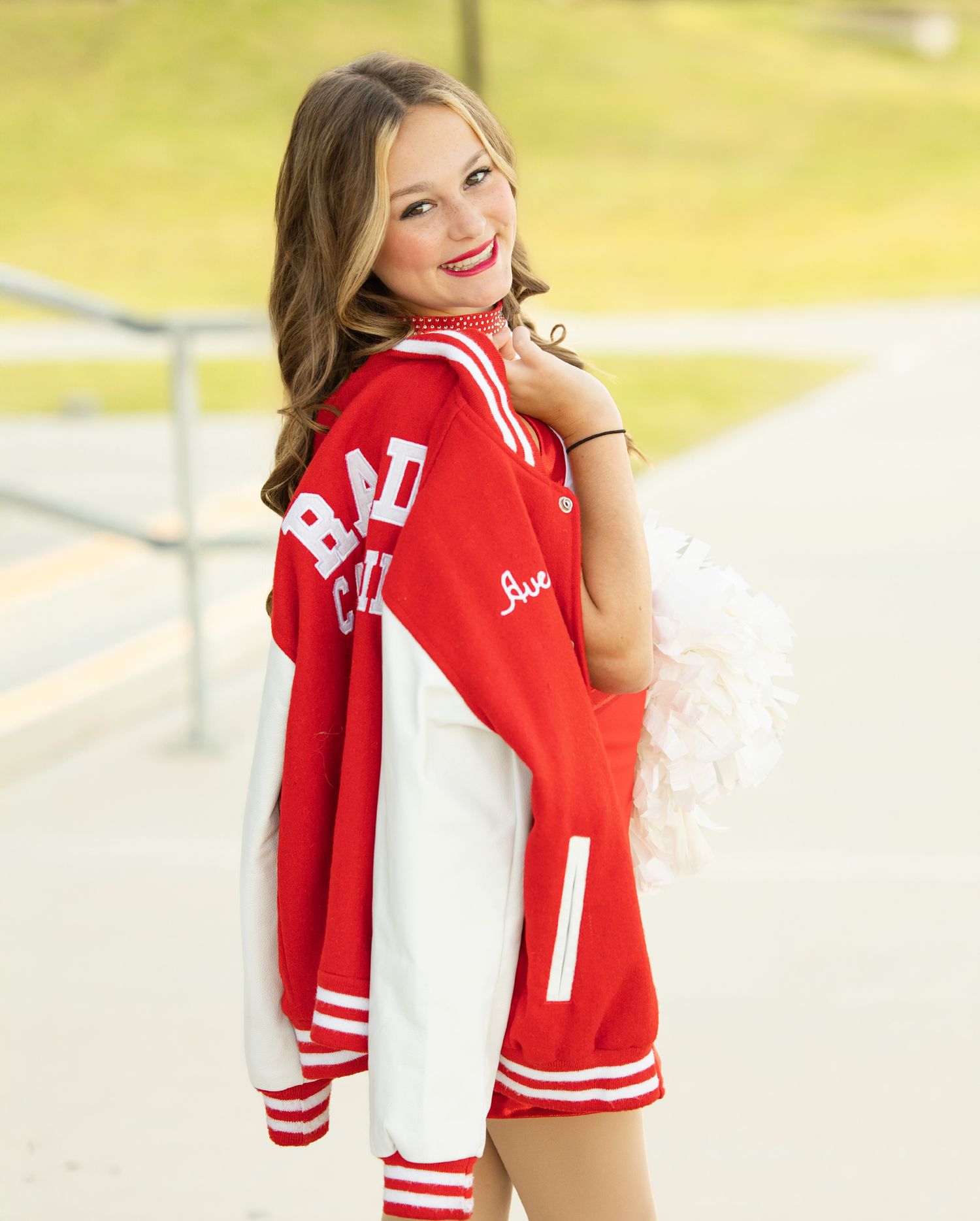 A red and white varsity letterman jacket is displayed in multiple poses against a bright outdoor background.