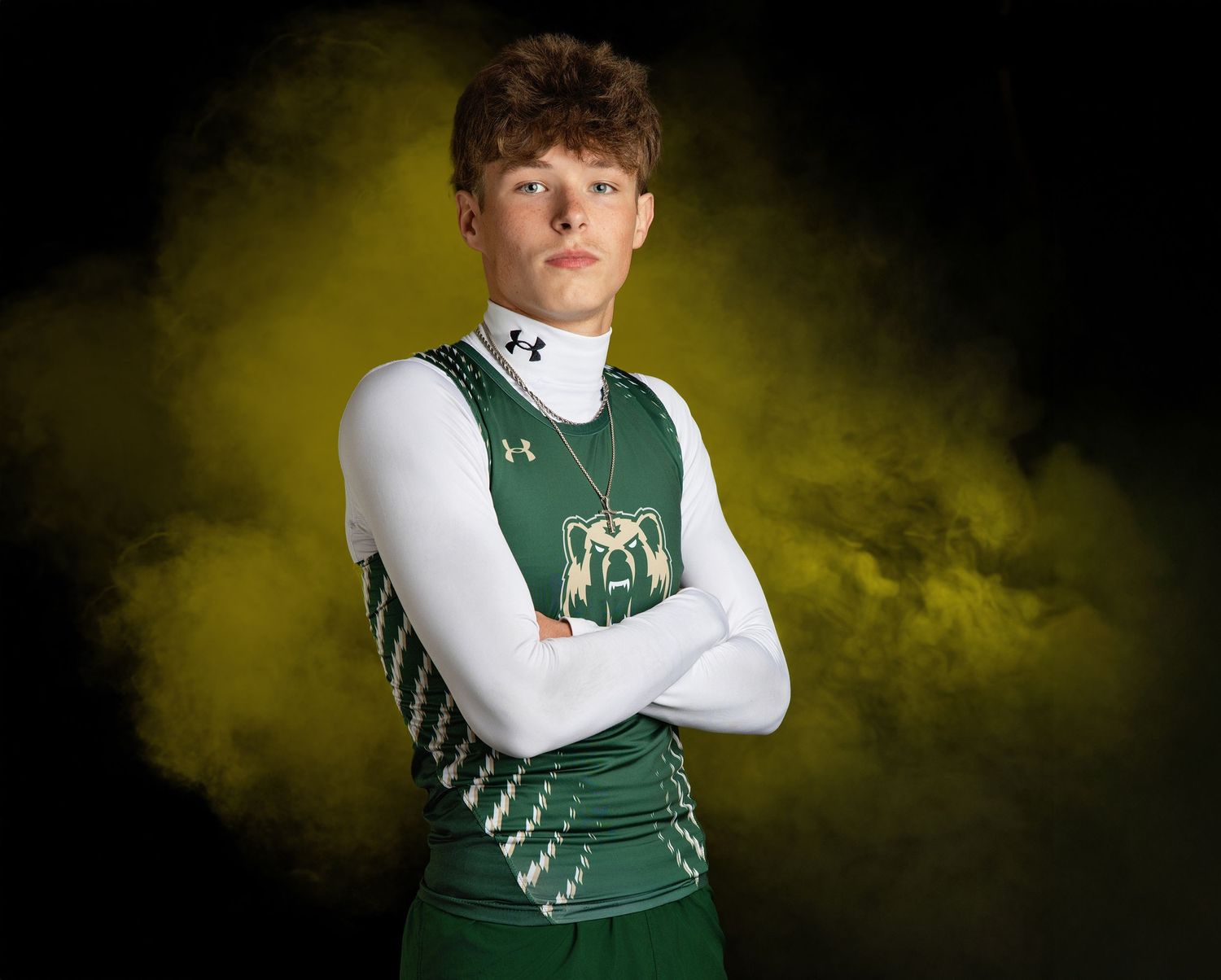 Dramatic sports portrait of LCM athlete in green and white uniform against dark yellow smoke background.