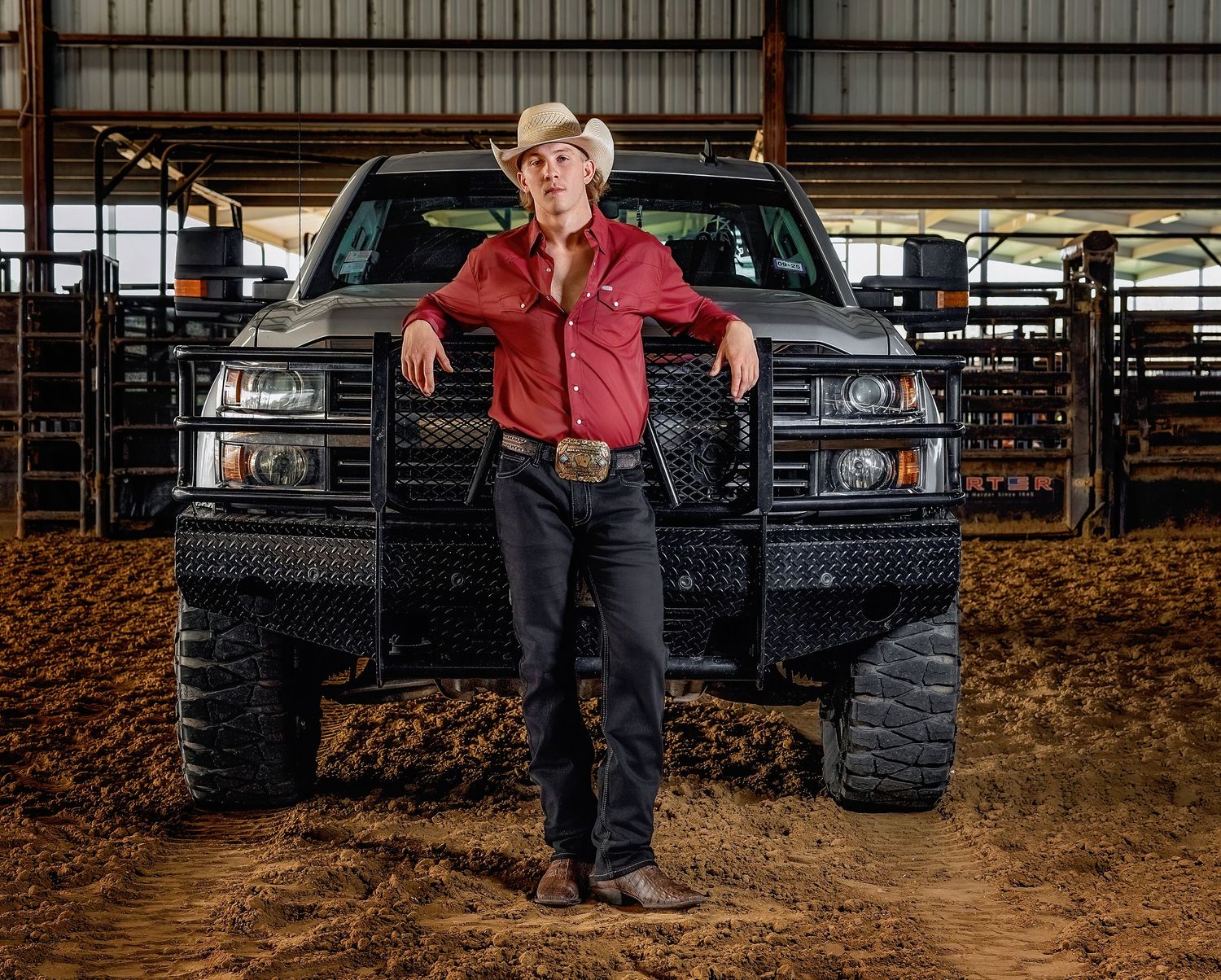 LCM Senior in western wear stands in front of a black pickup truck in a barn setting.