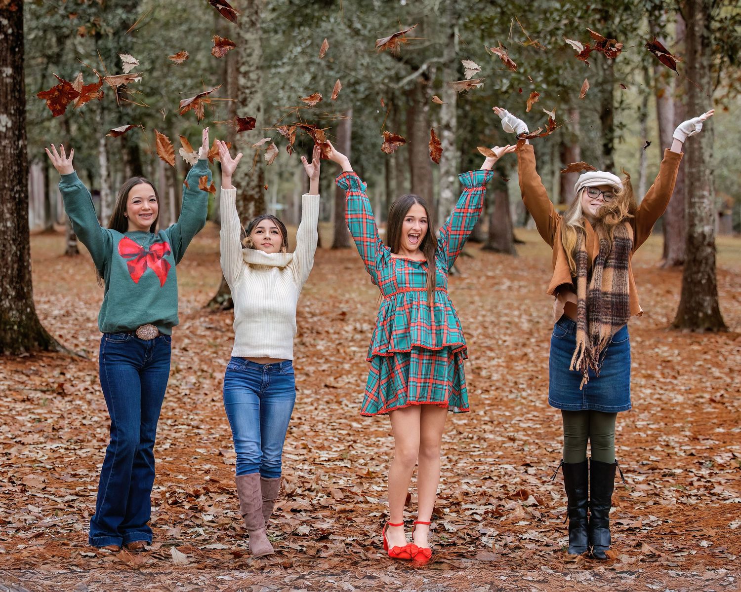 Group of friends throw autumn leaves in the air while standing in a wooded area.