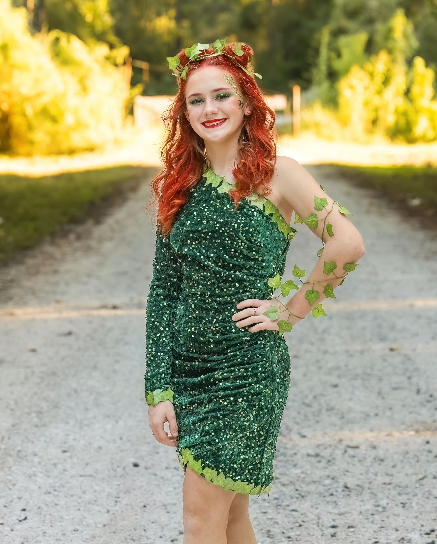 A photoshoot on a dirt path featuring someone in a sparkly green costume with autumn foliage.
