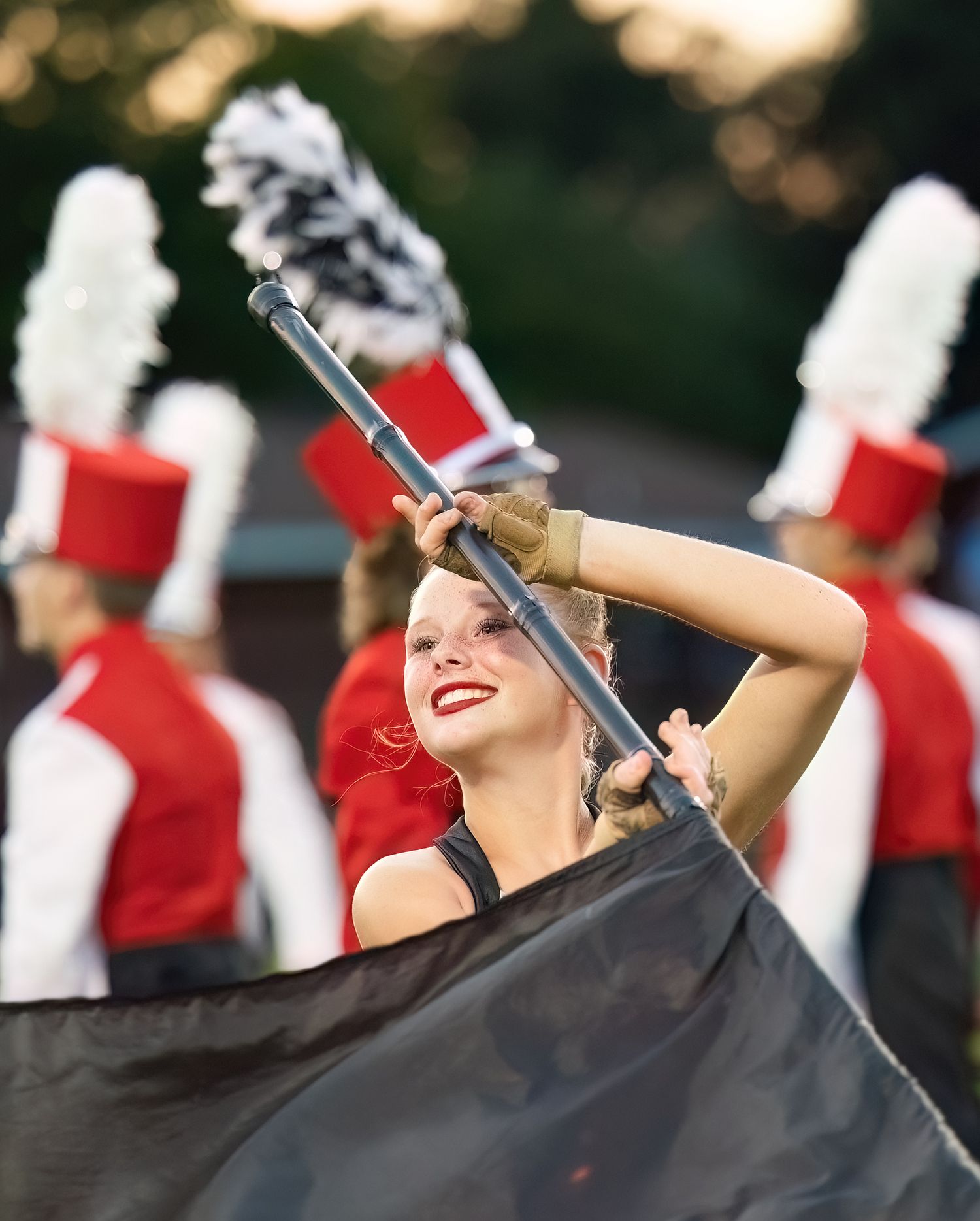 Bridge City High School Color Guard performs in red and white uniforms twirling flags during a halftime show.