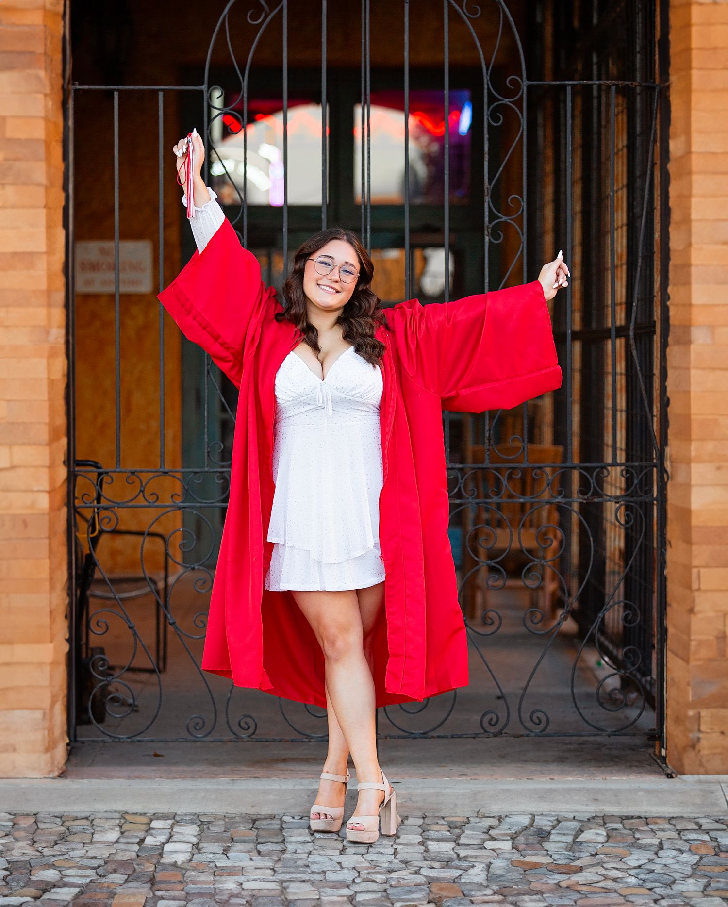 A series of three photos showing a person in a red graduation gown posing joyfully against a brick building entrance.