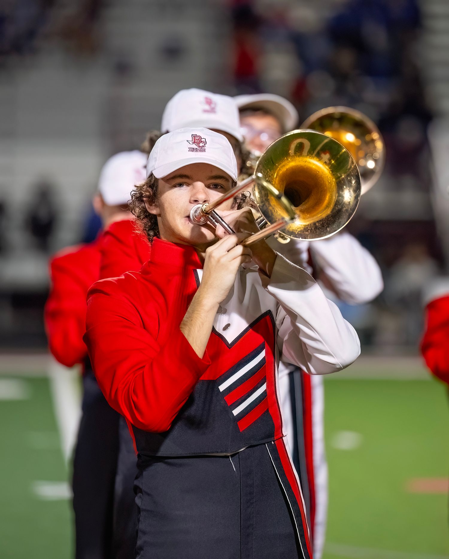 Band member plays trumpet while wearing a red and black marching uniform.