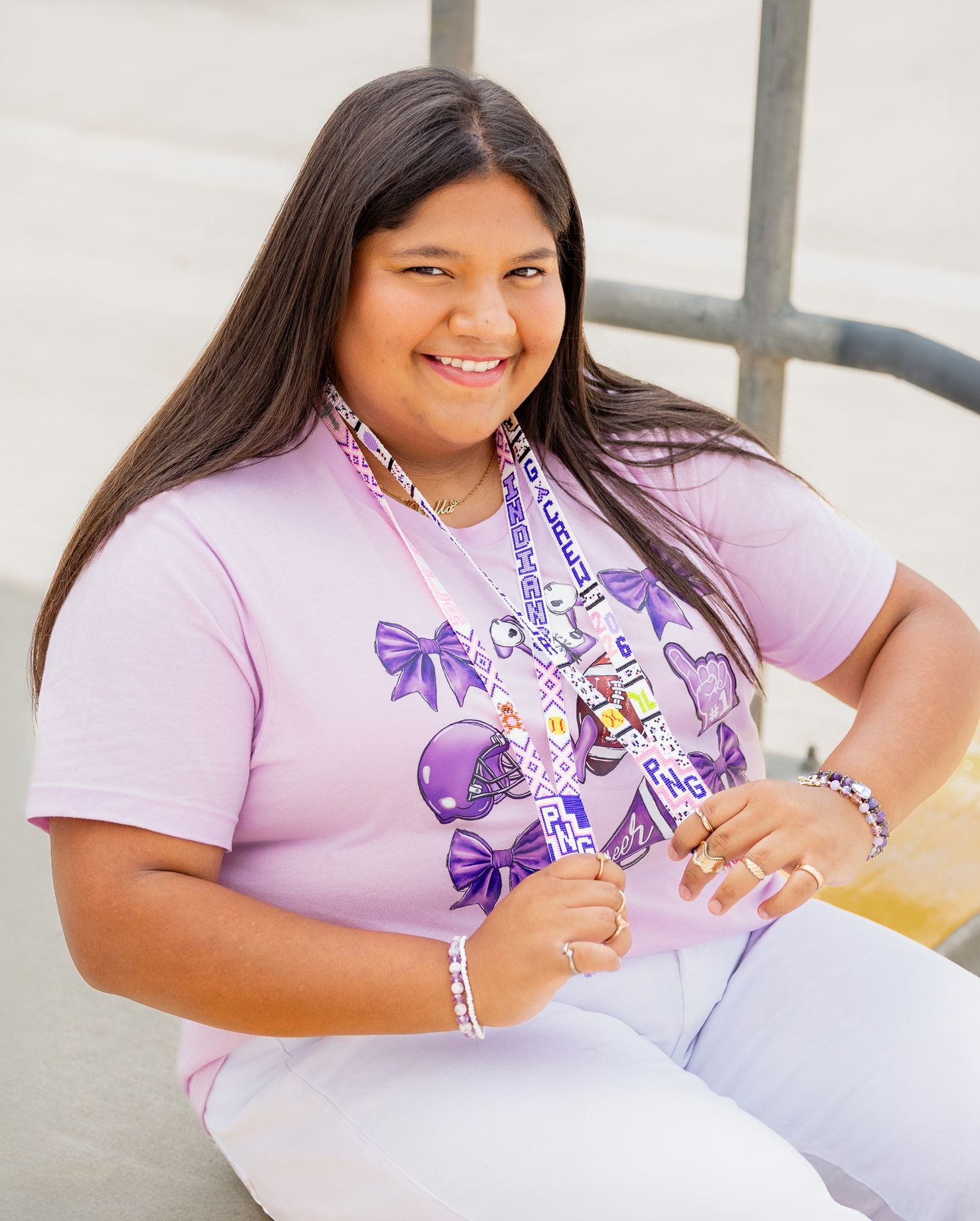 Student wearing purple and white bow-themed shirt poses during outdoor photo session.