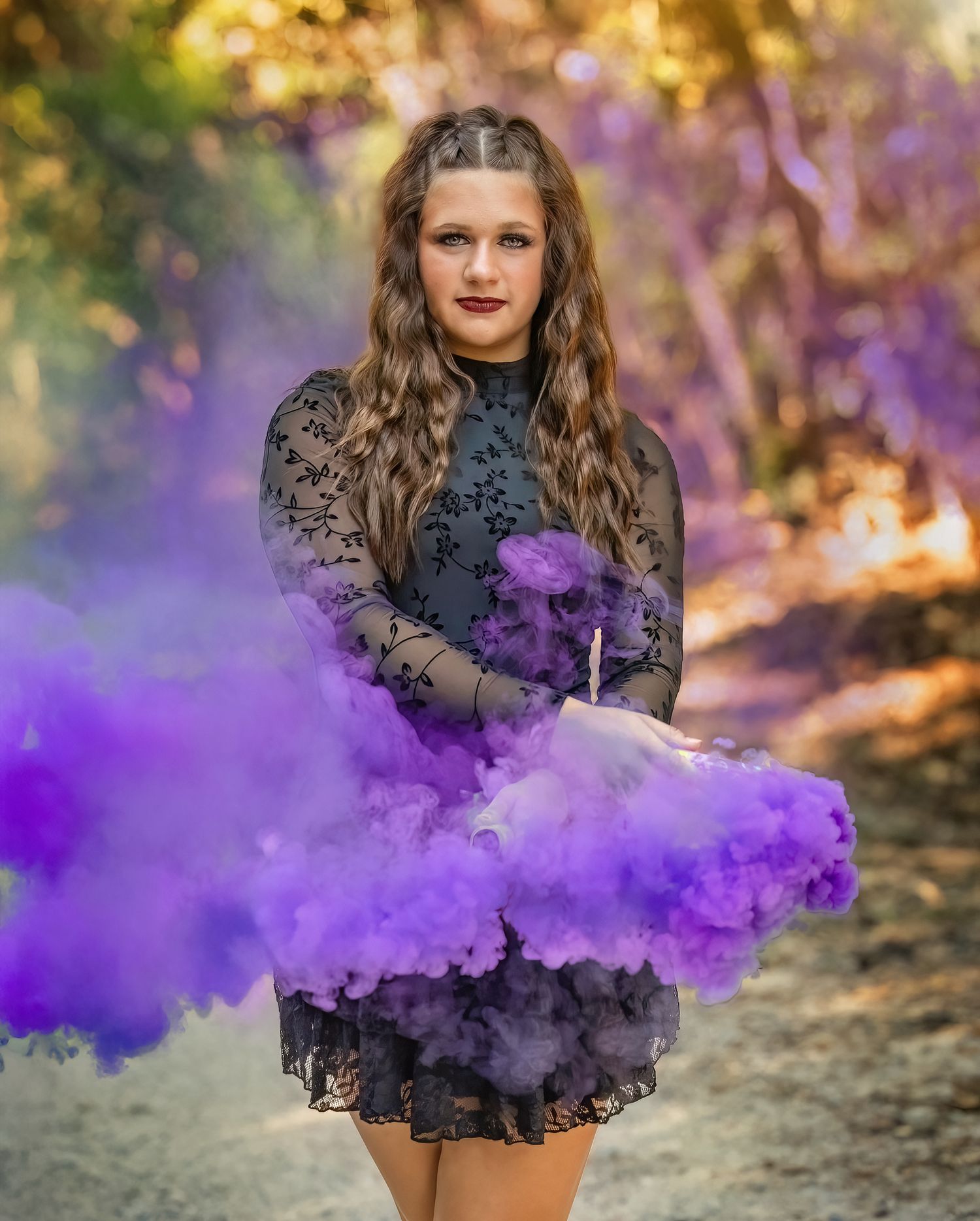 Purple smoke bomb creates dramatic effect in outdoor photoshoot with black lace dress and autumn backdrop.